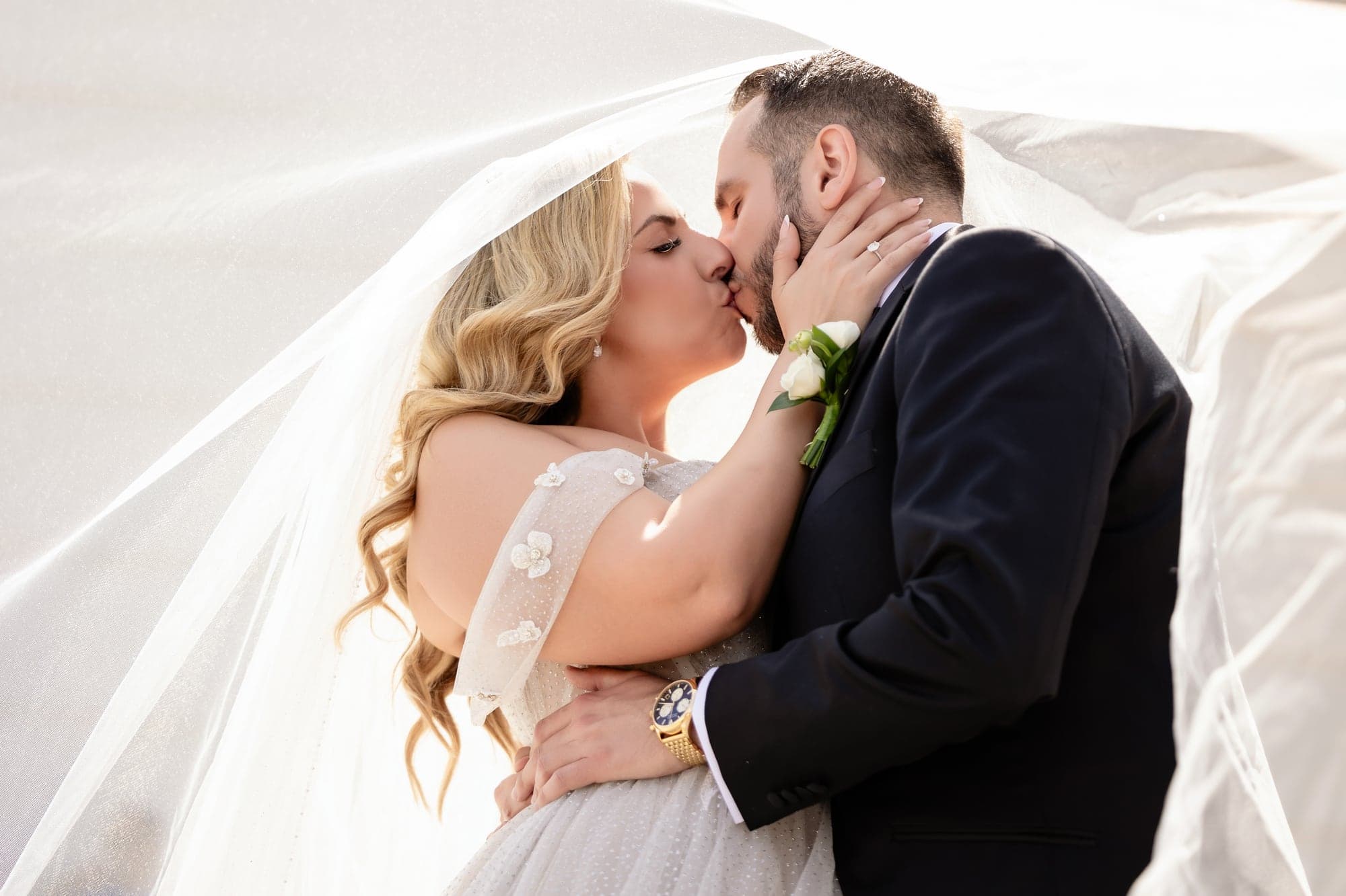 Eliz and Haig kissing beneath her veil after their Armenian wedding ceremony