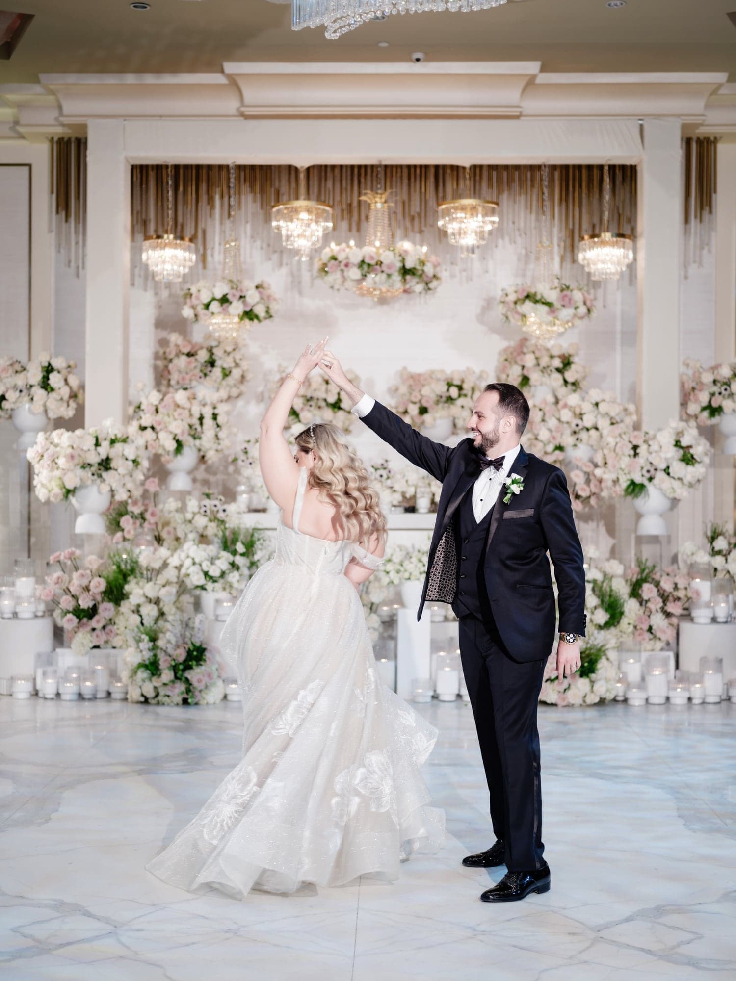 Eliz and Haig dancing in front of white flowers and chandeliers at Grand Venue
