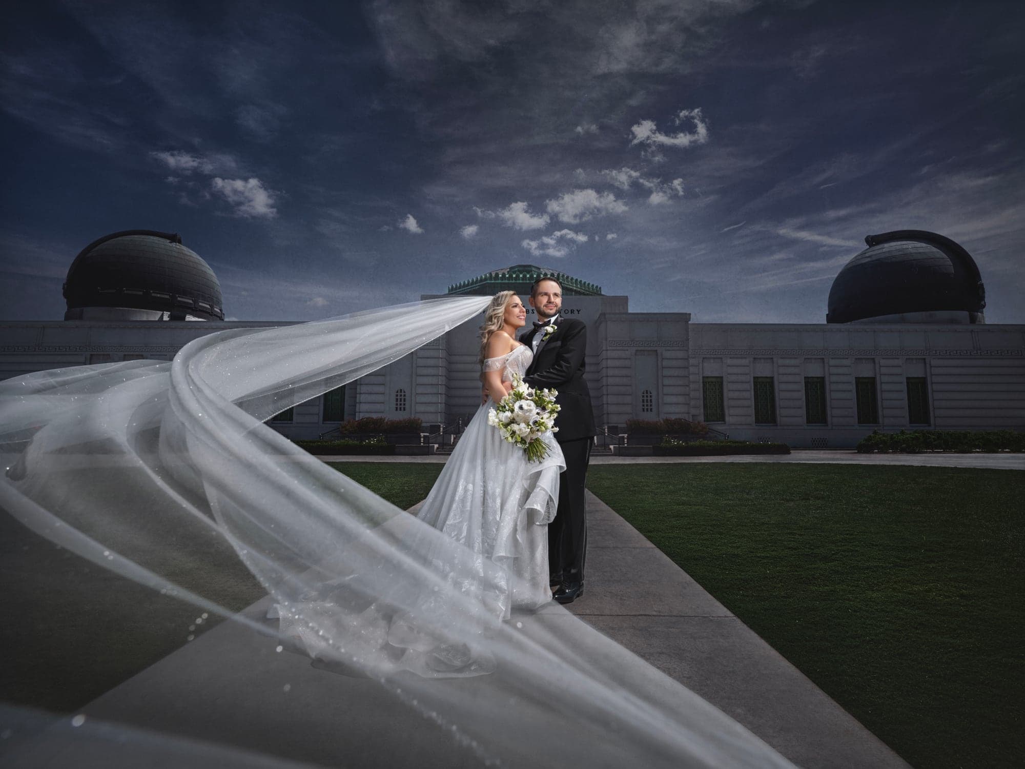Eliz and Haig standing beneath a sweeping veil at Griffith Observatory after their Armenian wedding ceremony