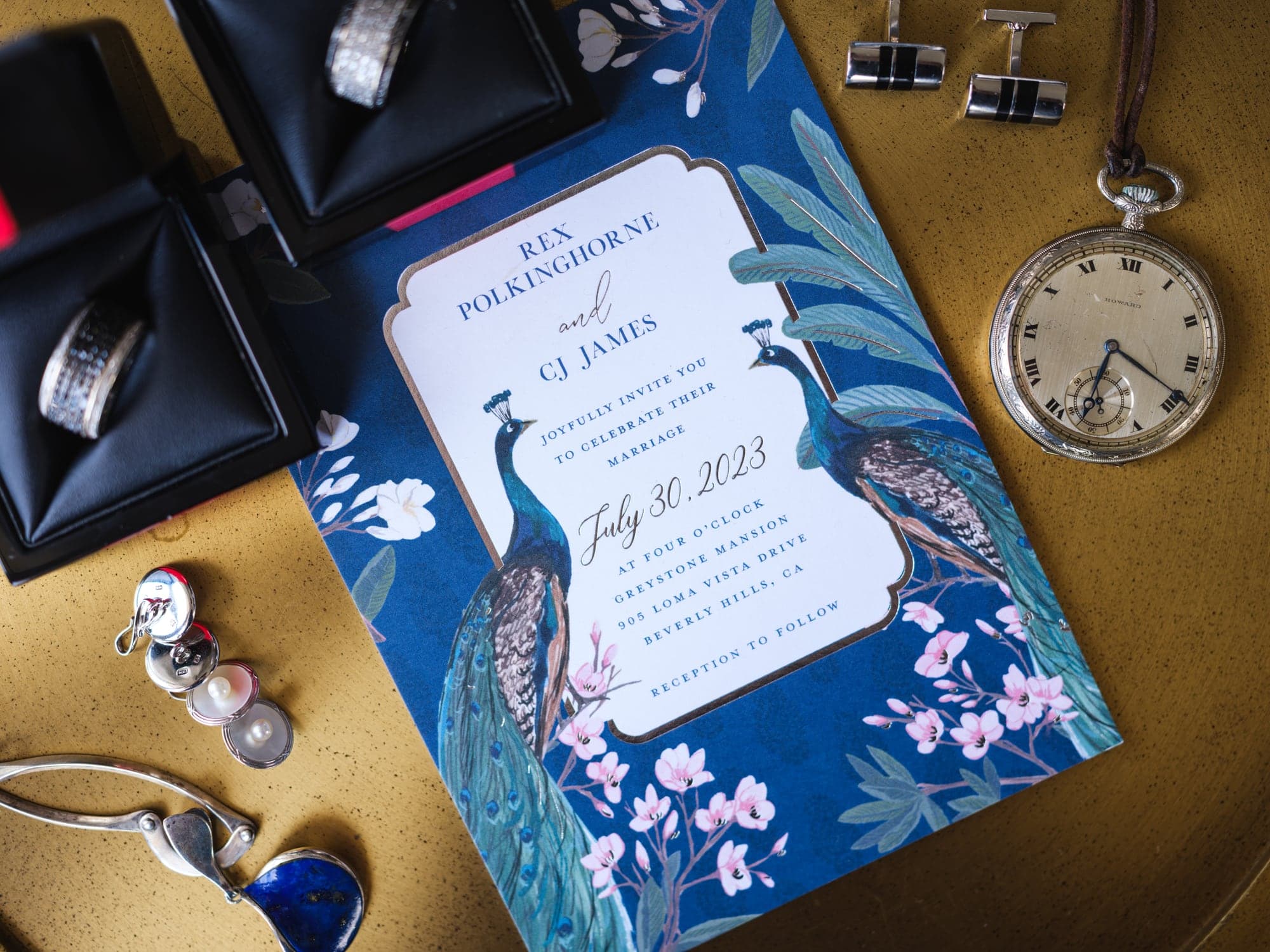 CJ and Rex's rings, watches, cuff links, and blue wedding program arranged before the ceremony