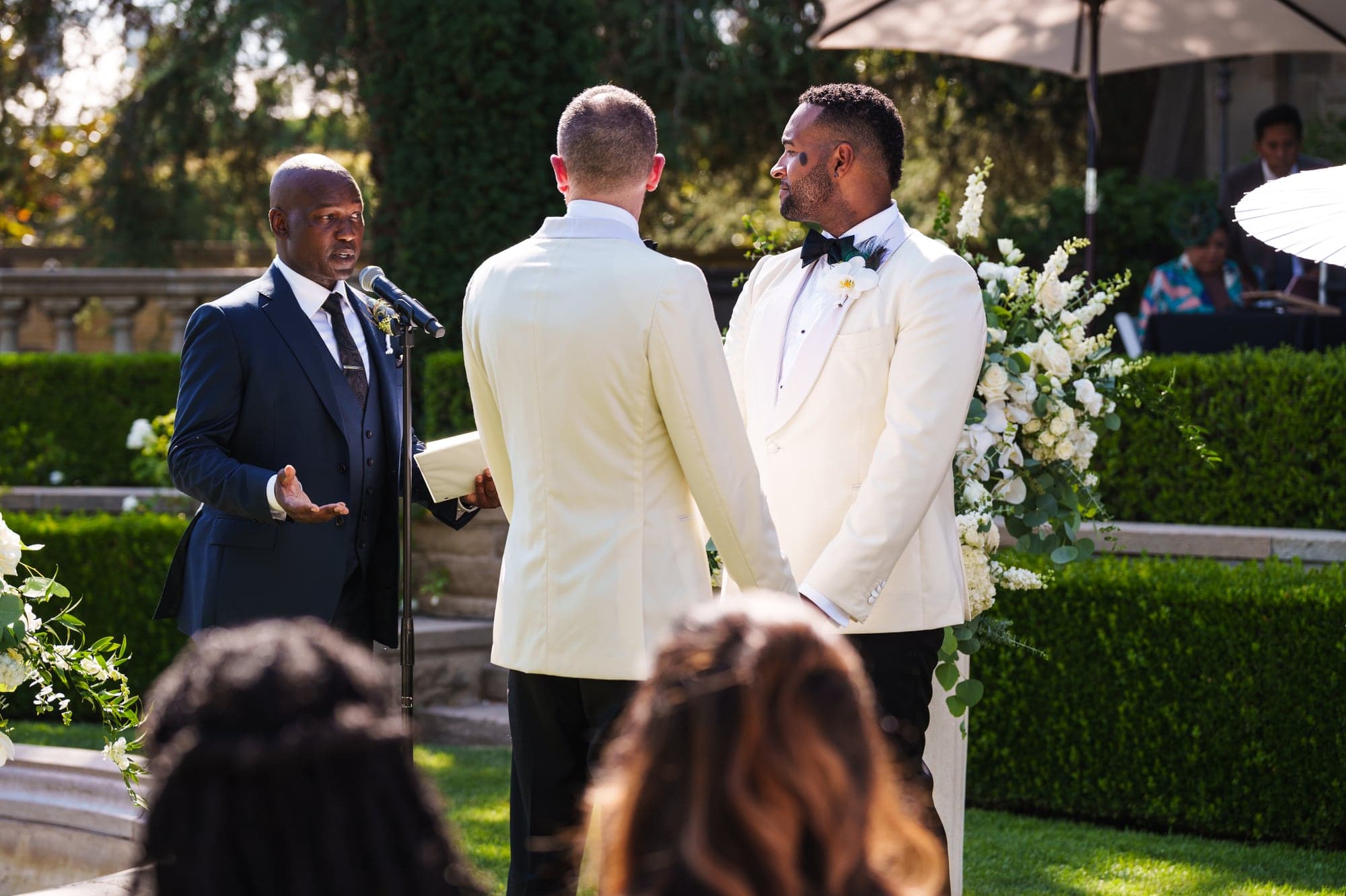 CJ and Rex facing one another during their flower-lined Greystone Mansion ceremony
