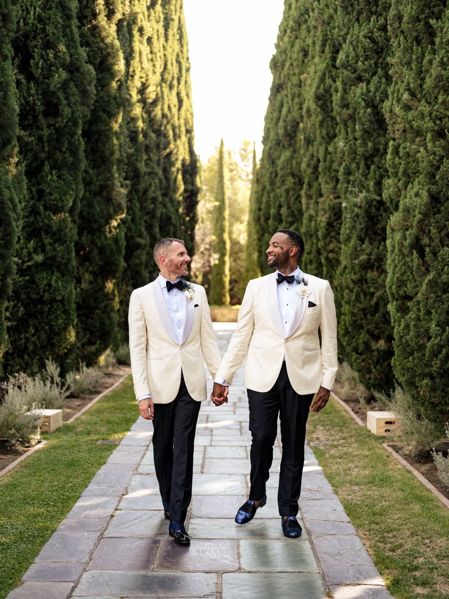 CJ and Rex walking together between tall cypress trees at Greystone Mansion
