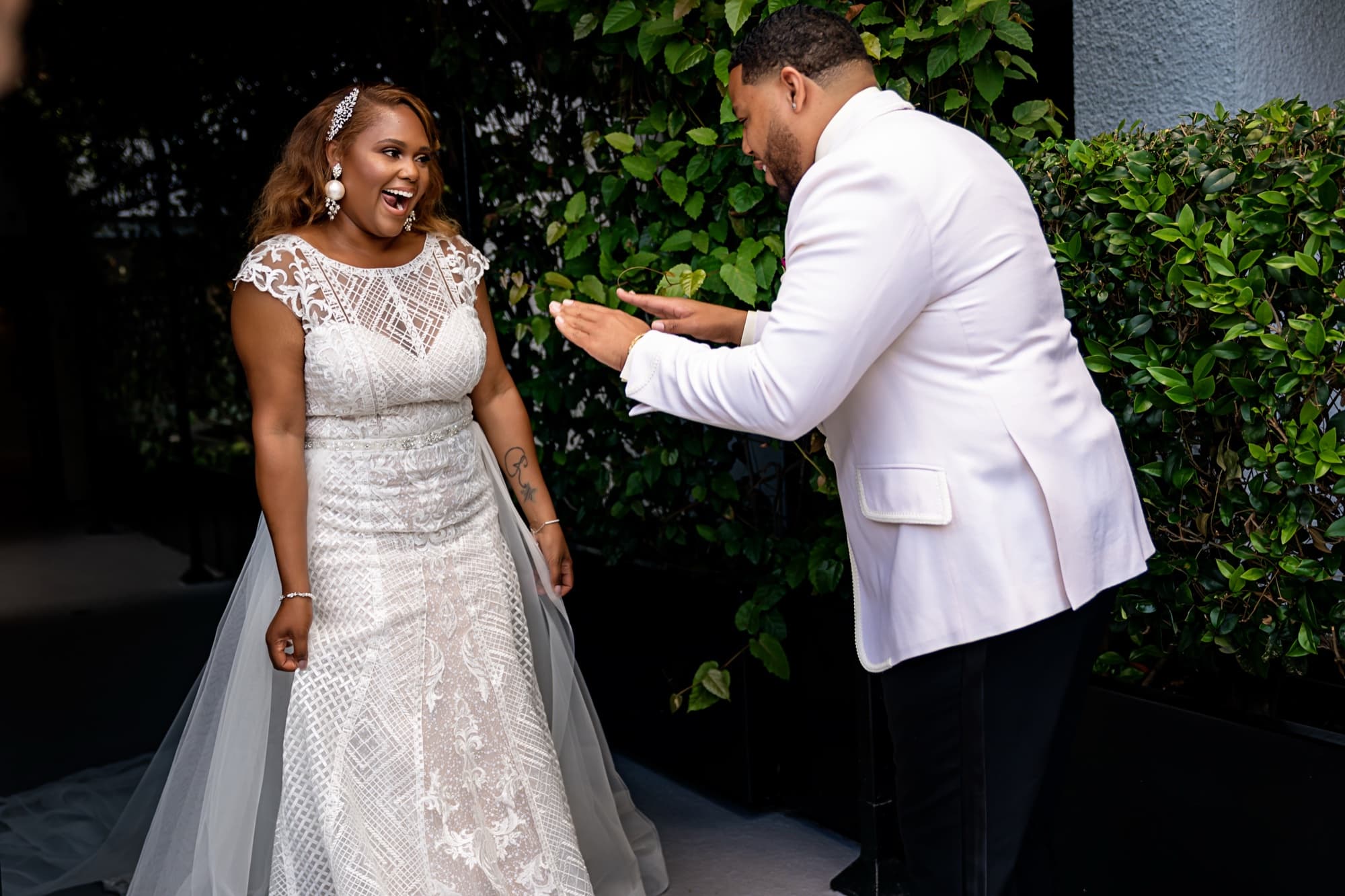Jarell in his white dinner jacket adjusting Shaniece's beaded gown in the garden as she laughs