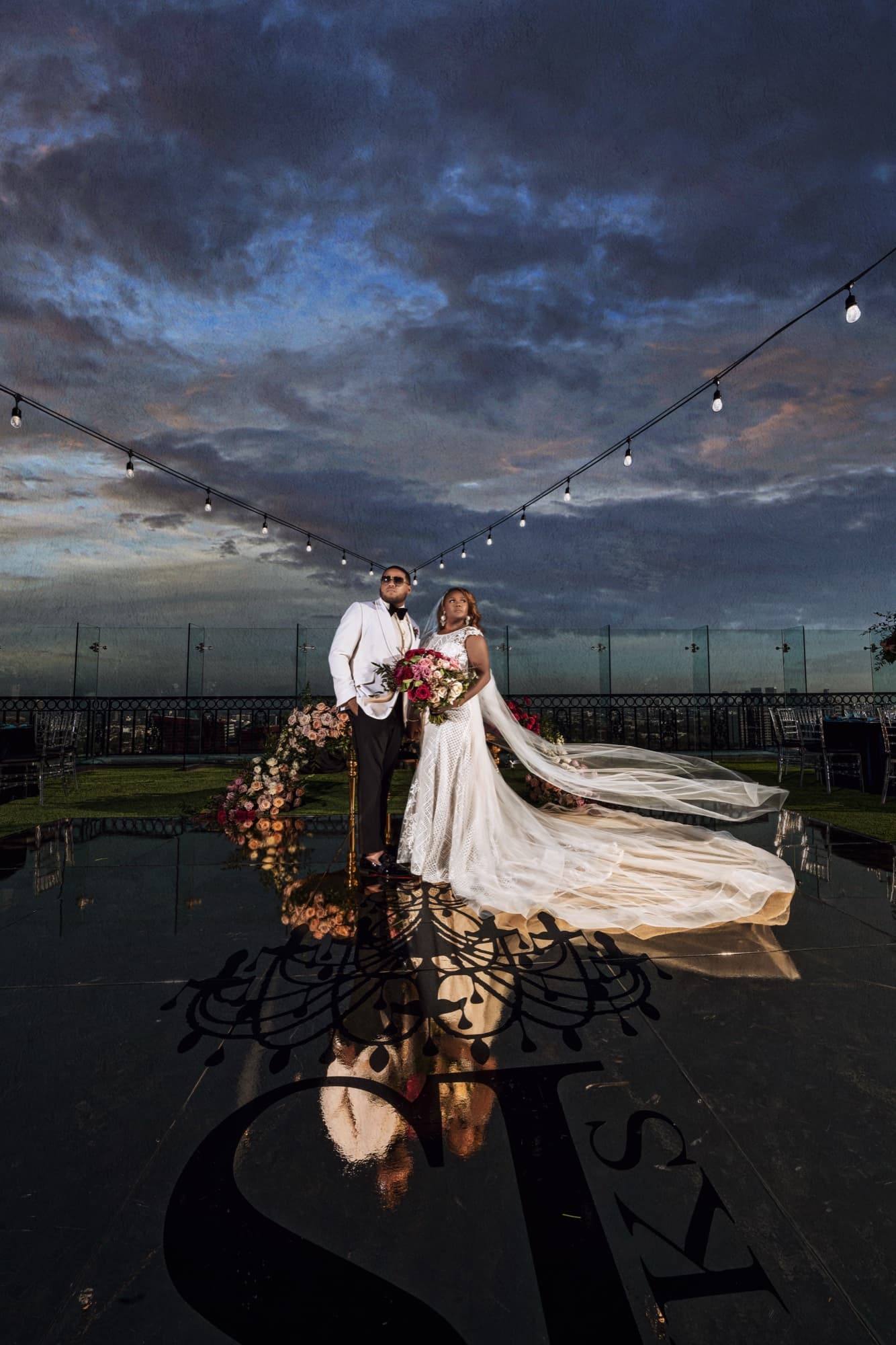 Shaniece and Jarell on the London West Hollywood rooftop at dusk under string lights with their monogram reflected beneath them