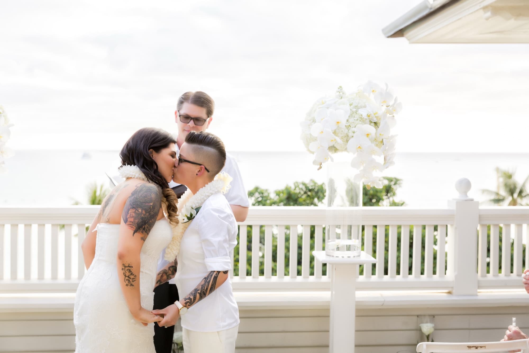 Amanda and Shauna sharing their first kiss on the oceanfront veranda with white orchids and the Pacific behind them