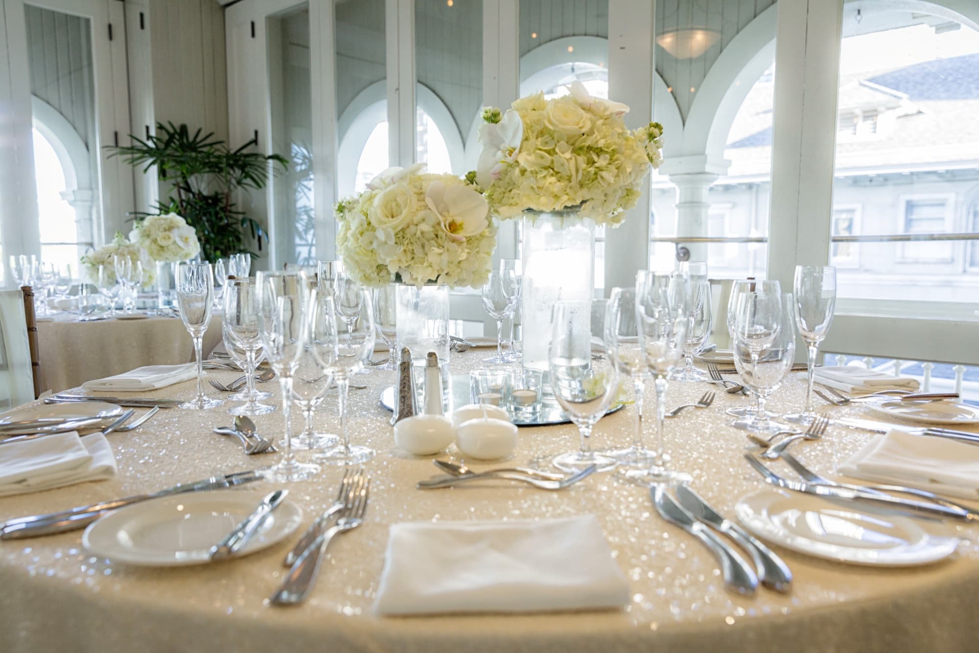 Oceanview reception room with arched windows, orchid centerpieces, and sparkling linens for Amanda and Shauna's Hawaii wedding