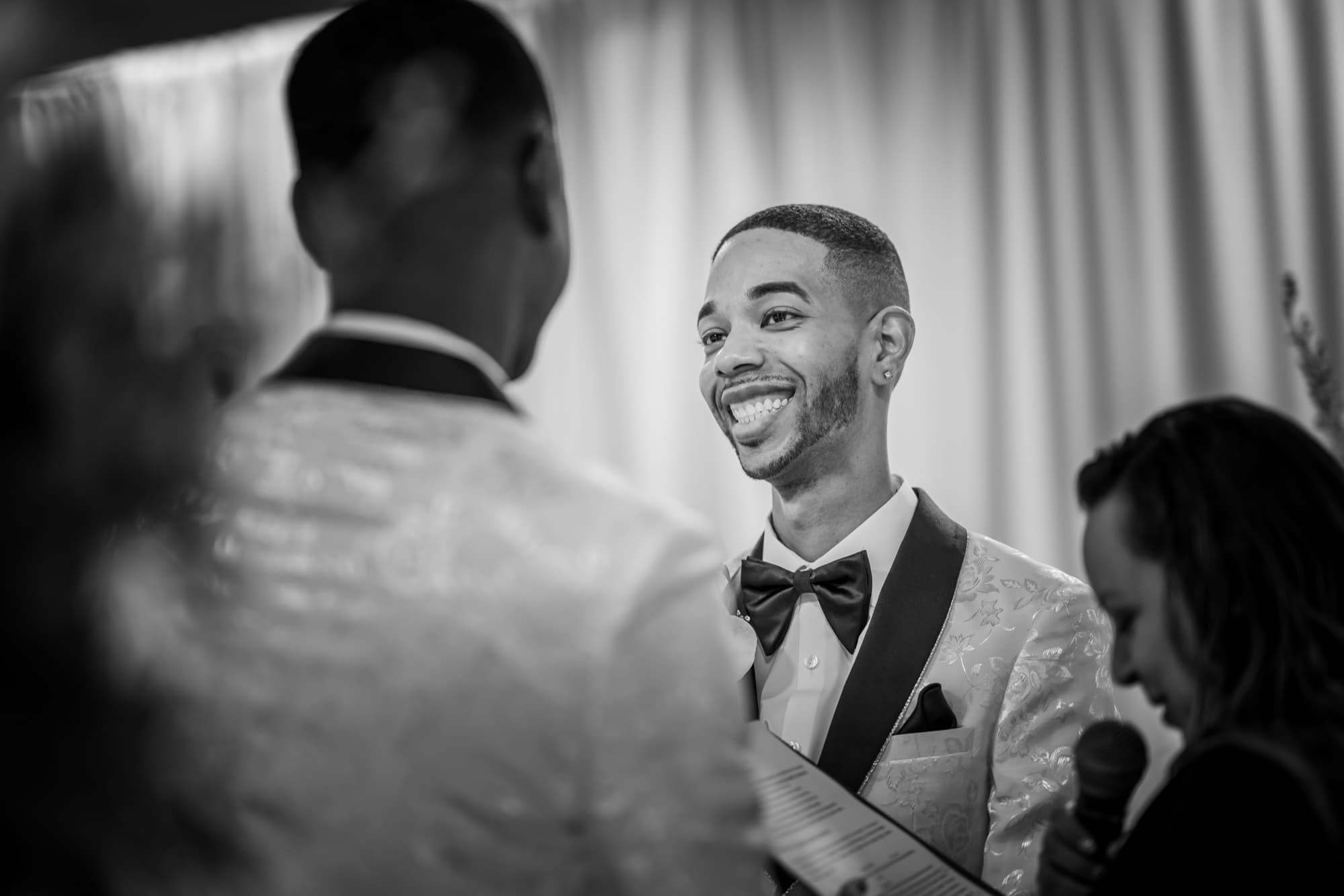 Anthony and Desmond laughing together during their wedding ceremony as the officiant speaks beside them