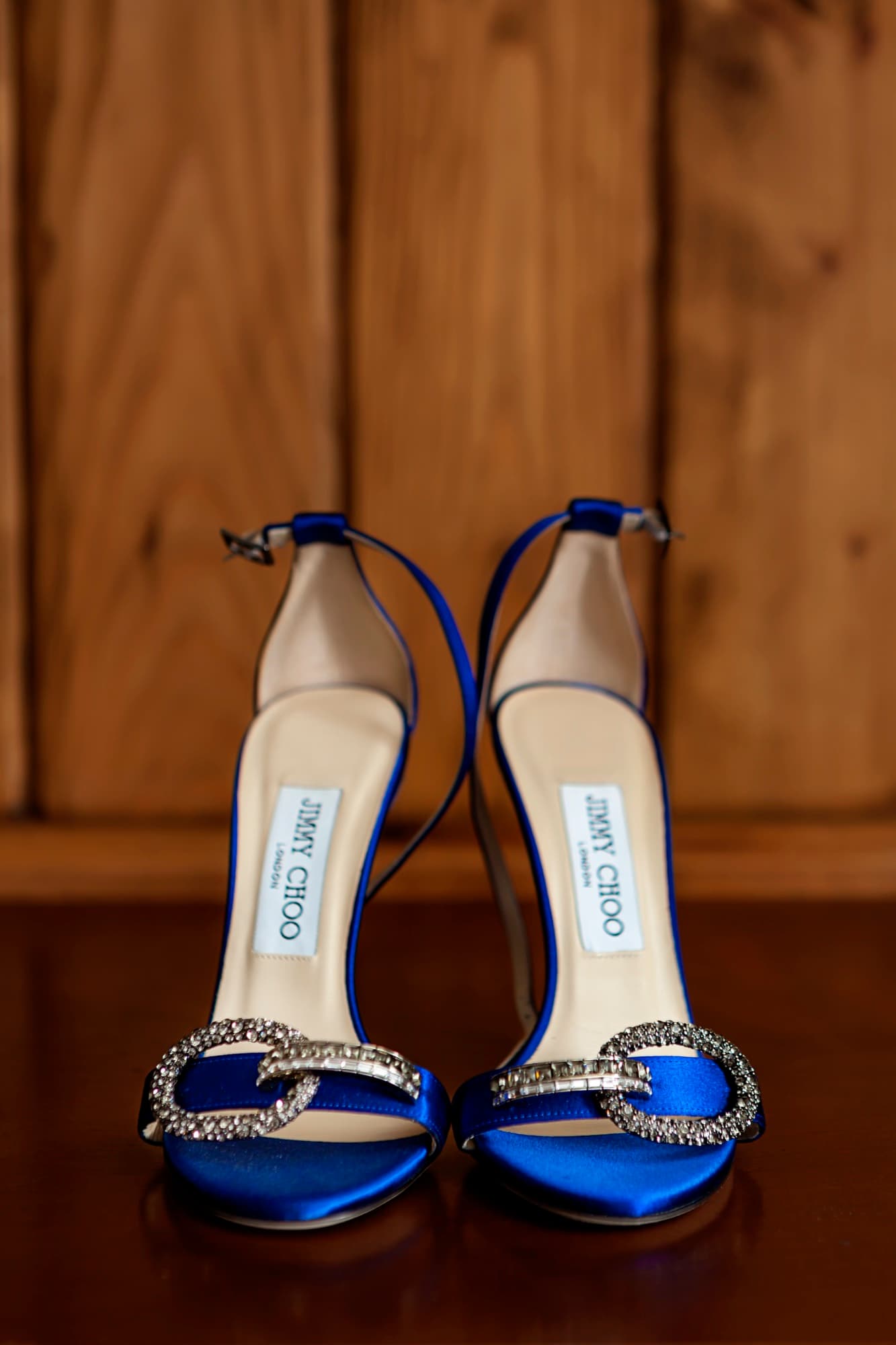 Electric blue Jimmy Choo bridal heels with crystal straps standing toe to toe on a wood table at Hummingbird Nest Ranch
