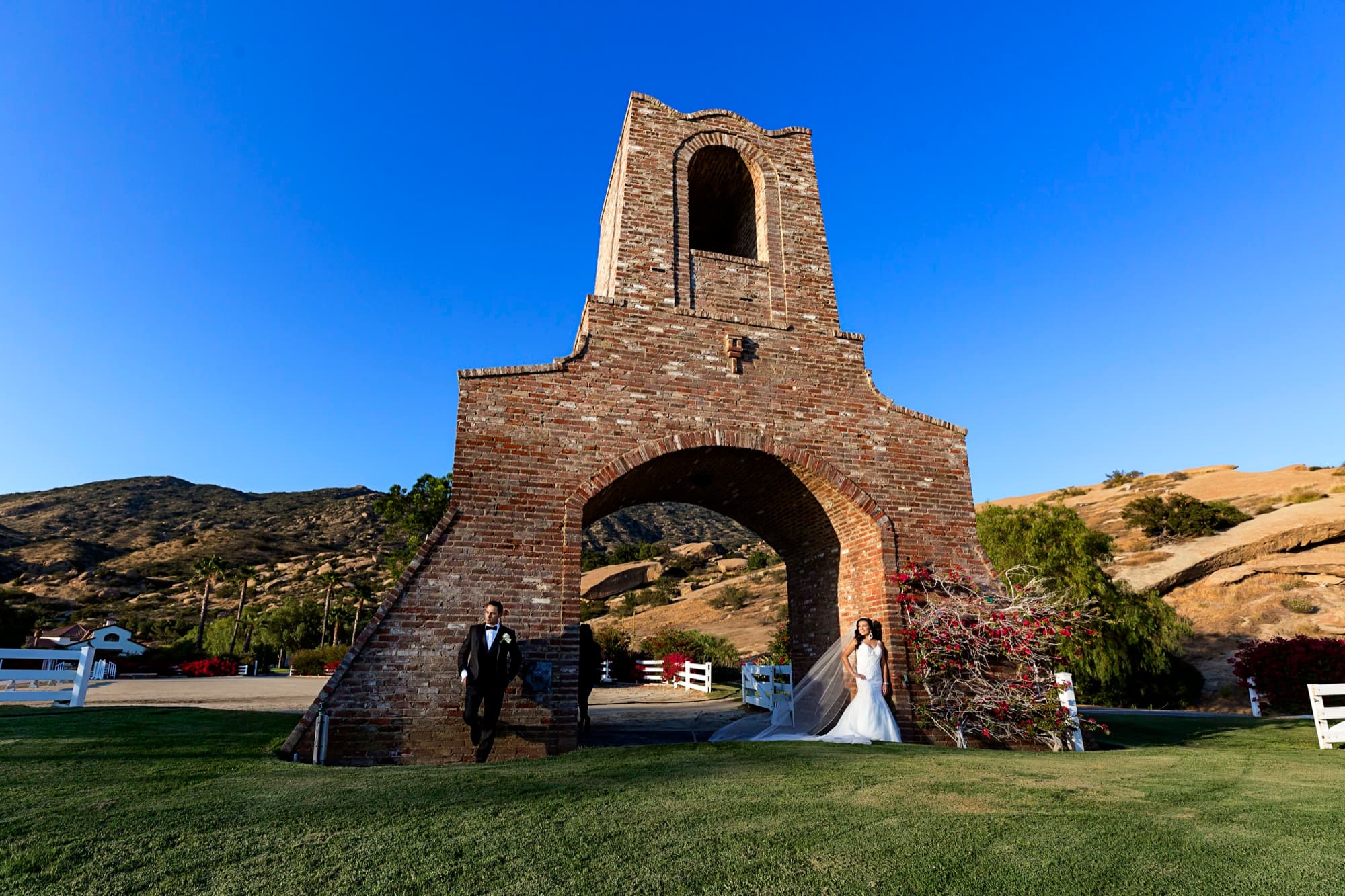 Bride and groom standing beneath the stone bell tower arch at Hummingbird Nest Ranch with the Santa Susana hills behind them
