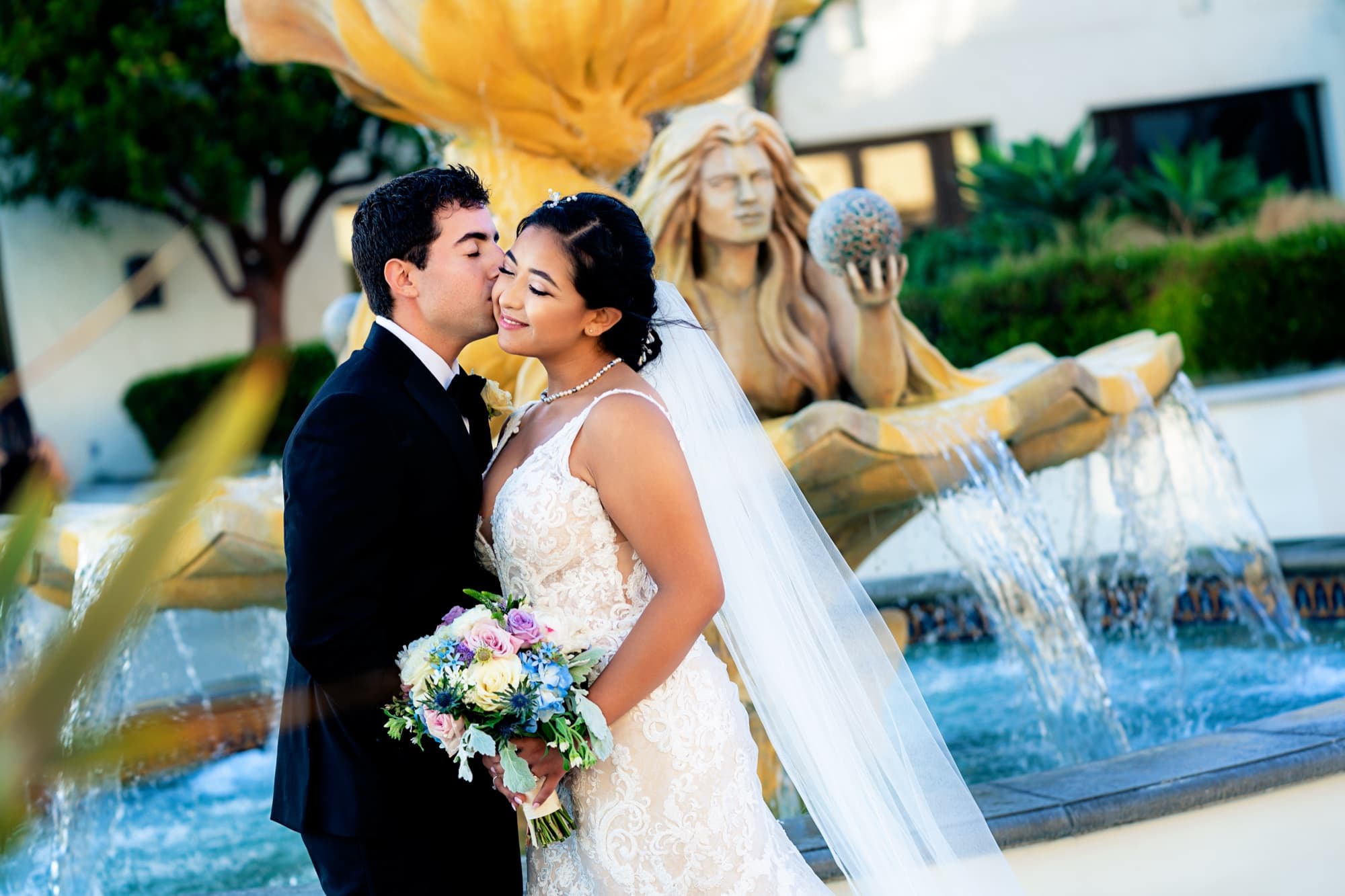 Navid kissing Ingrid beside the tiled mermaid fountain in the Spanish courtyard of the Hyatt Regency Huntington Beach