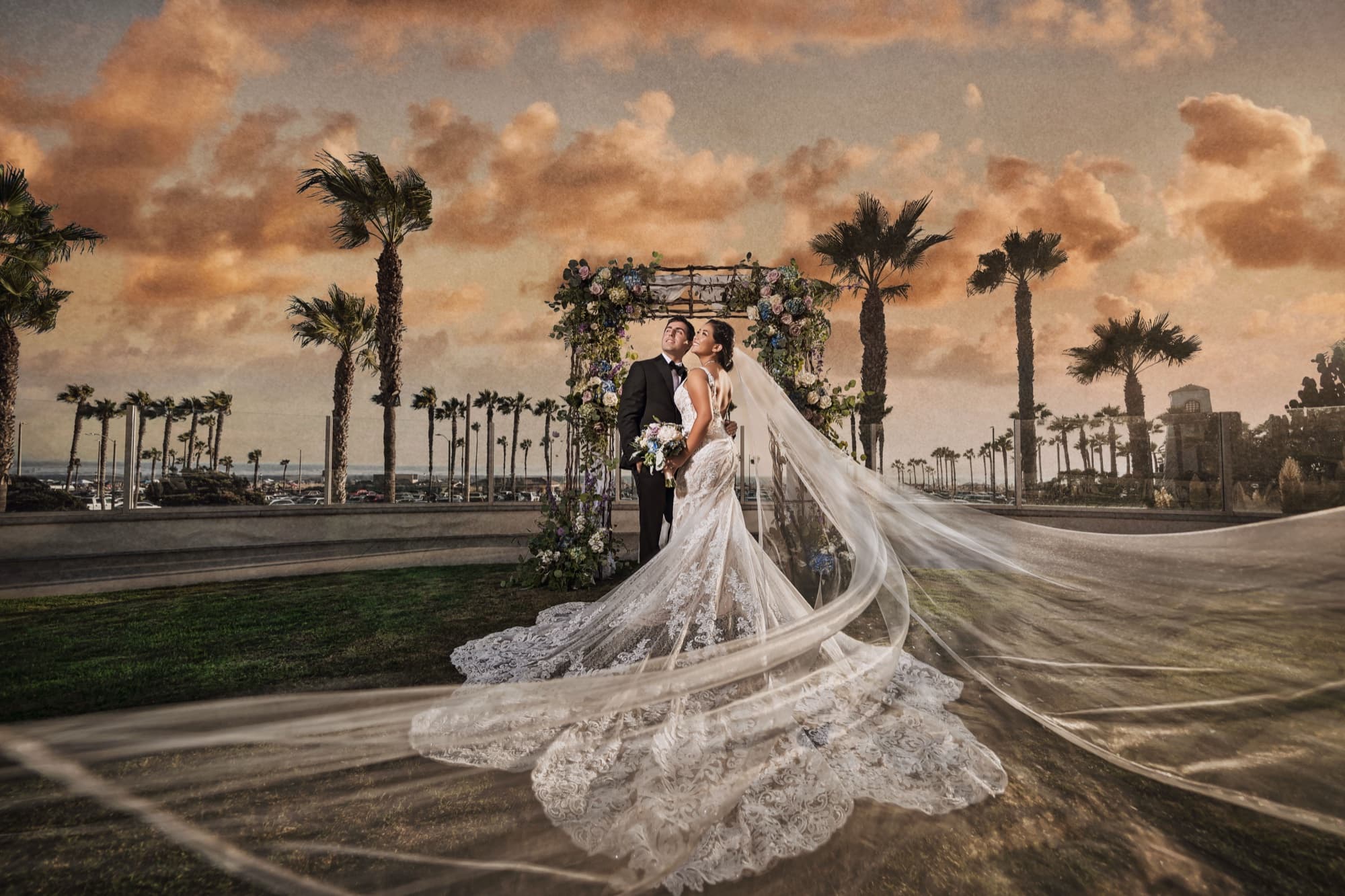 Ingrid's veil sweeping across the lawn at sunset with palm trees and the floral arch behind her at the Hyatt Huntington Beach