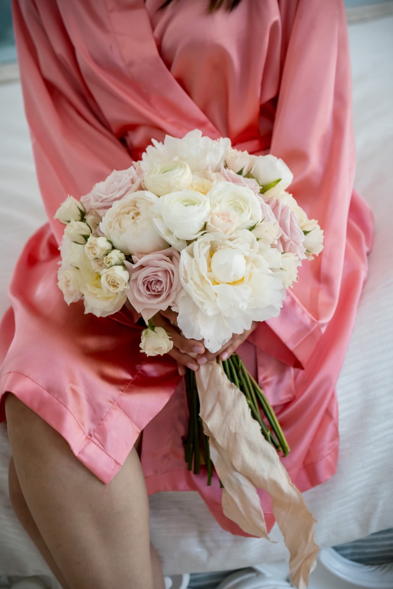 Noor's blush robe and bouquet of ivory roses and peonies tied with trailing ribbon