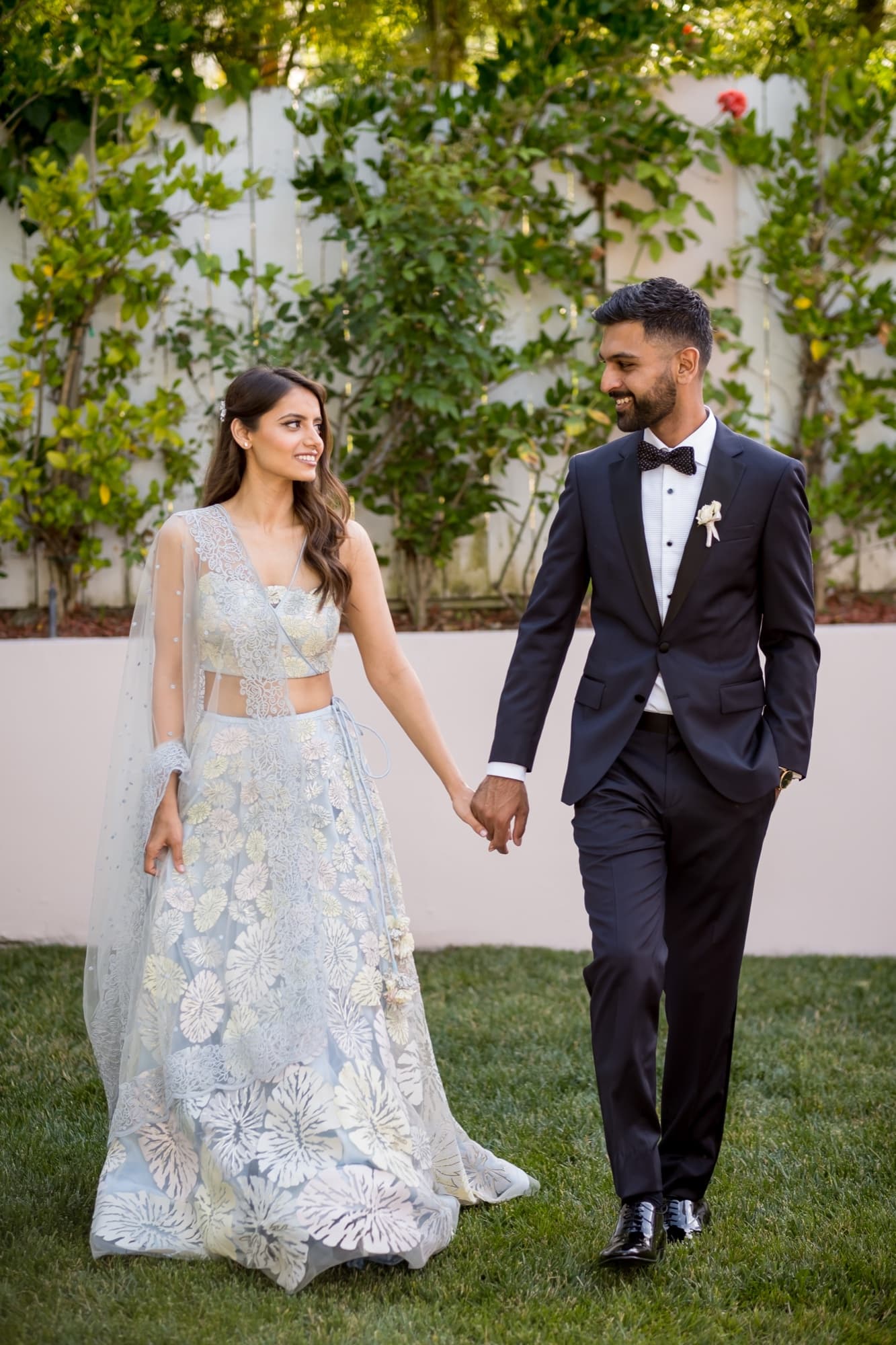 Noor in an embroidered ivory two-piece with a sheer dupatta walking hand in hand with Sheazad across the garden lawn