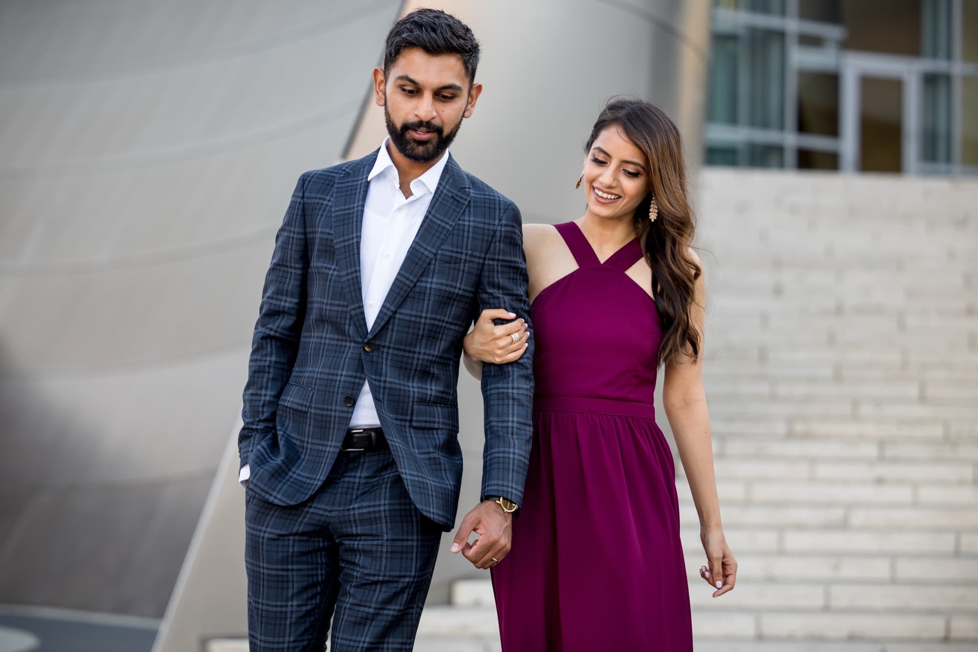 Noor in a deep burgundy gown holding Sheazad's arm against the steel curves of Walt Disney Concert Hall