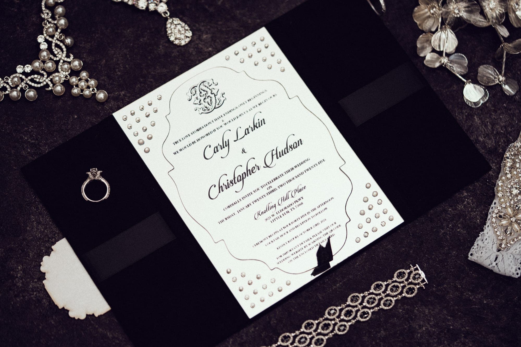 Carly and Christopher's crystal-studded wedding invitation with rings and jewelry on black velvet