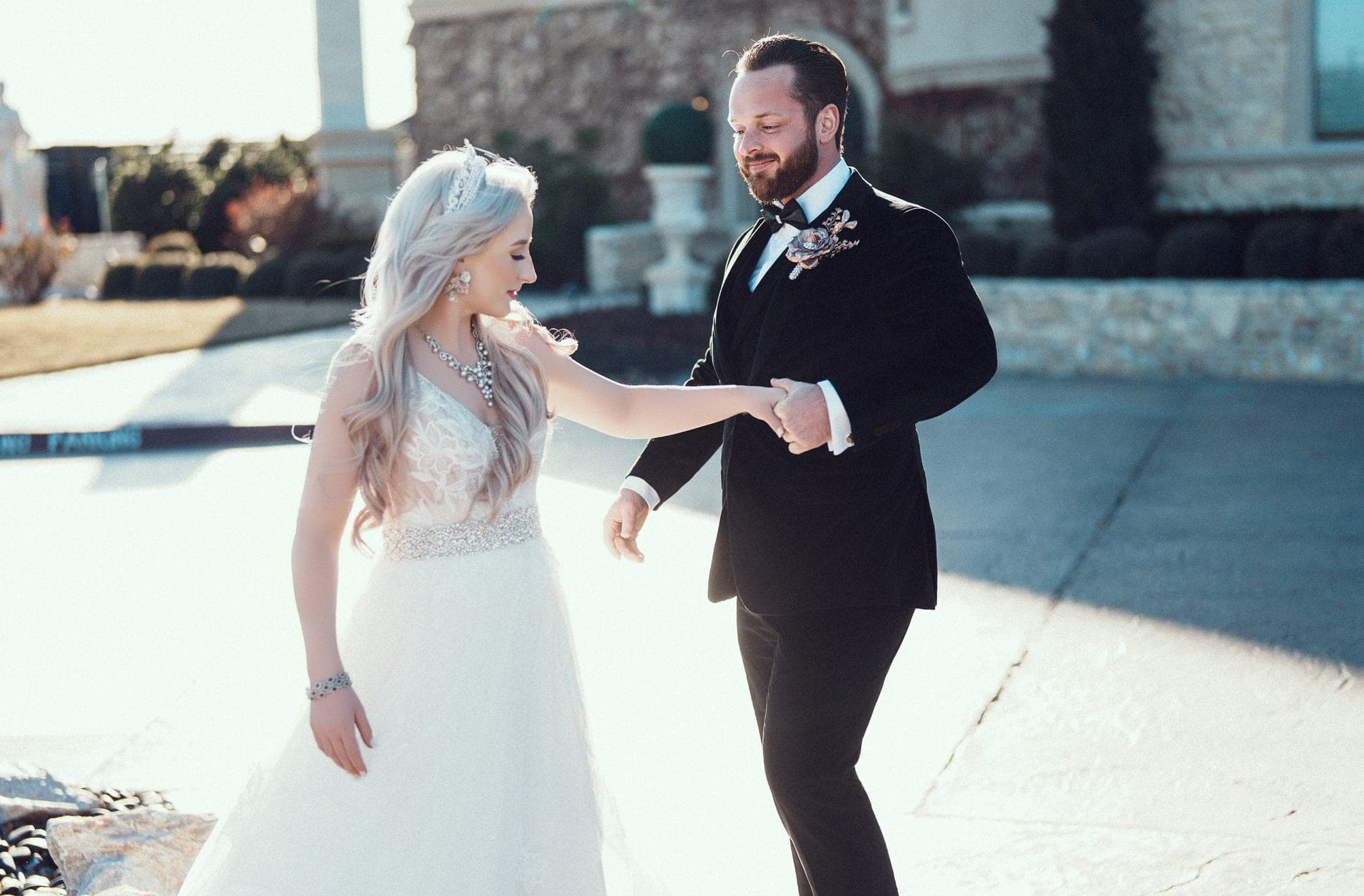 Carly and Christopher walking hand in hand through the sunlit courtyard