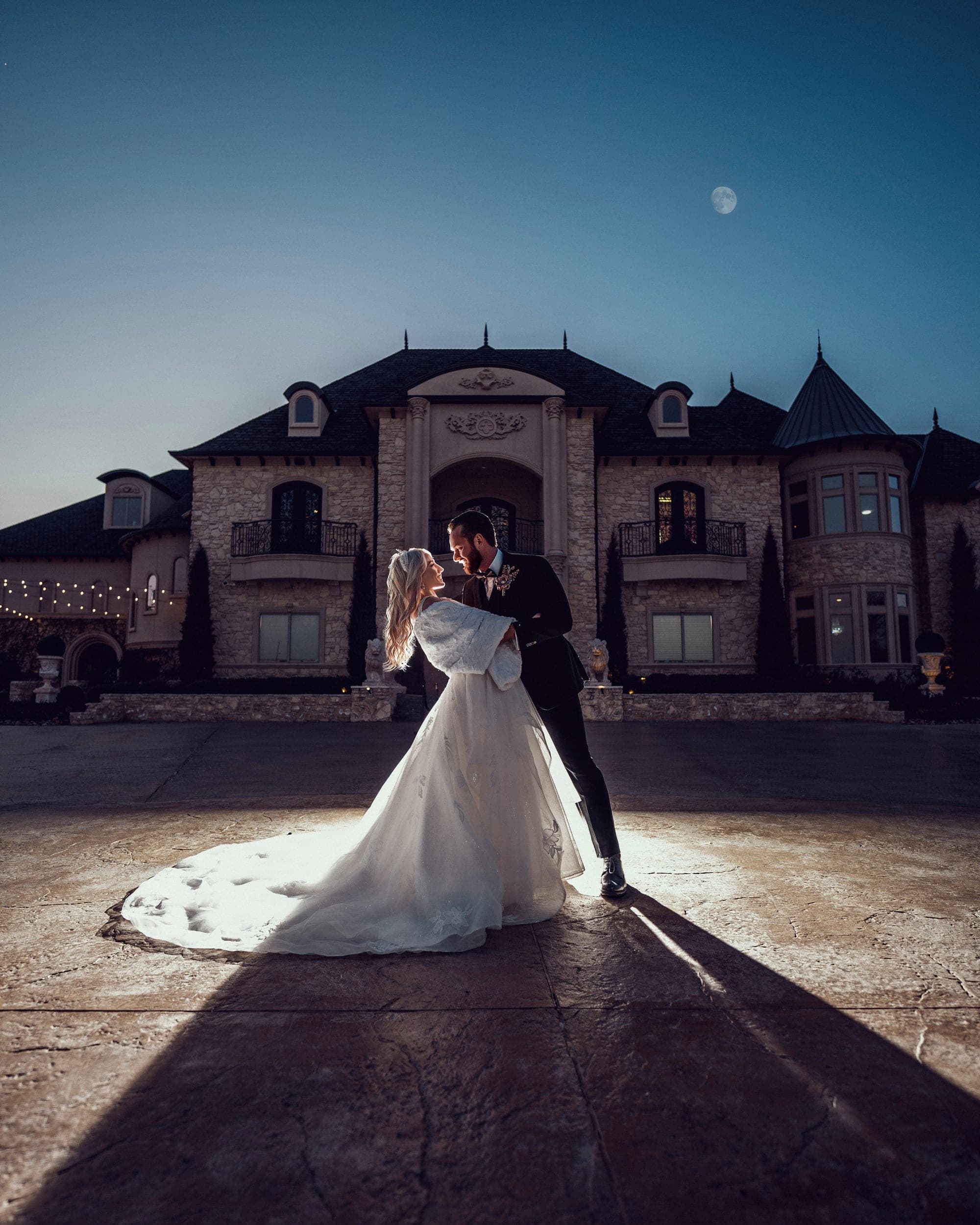 The couple at night in front of the lit château under a winter moon