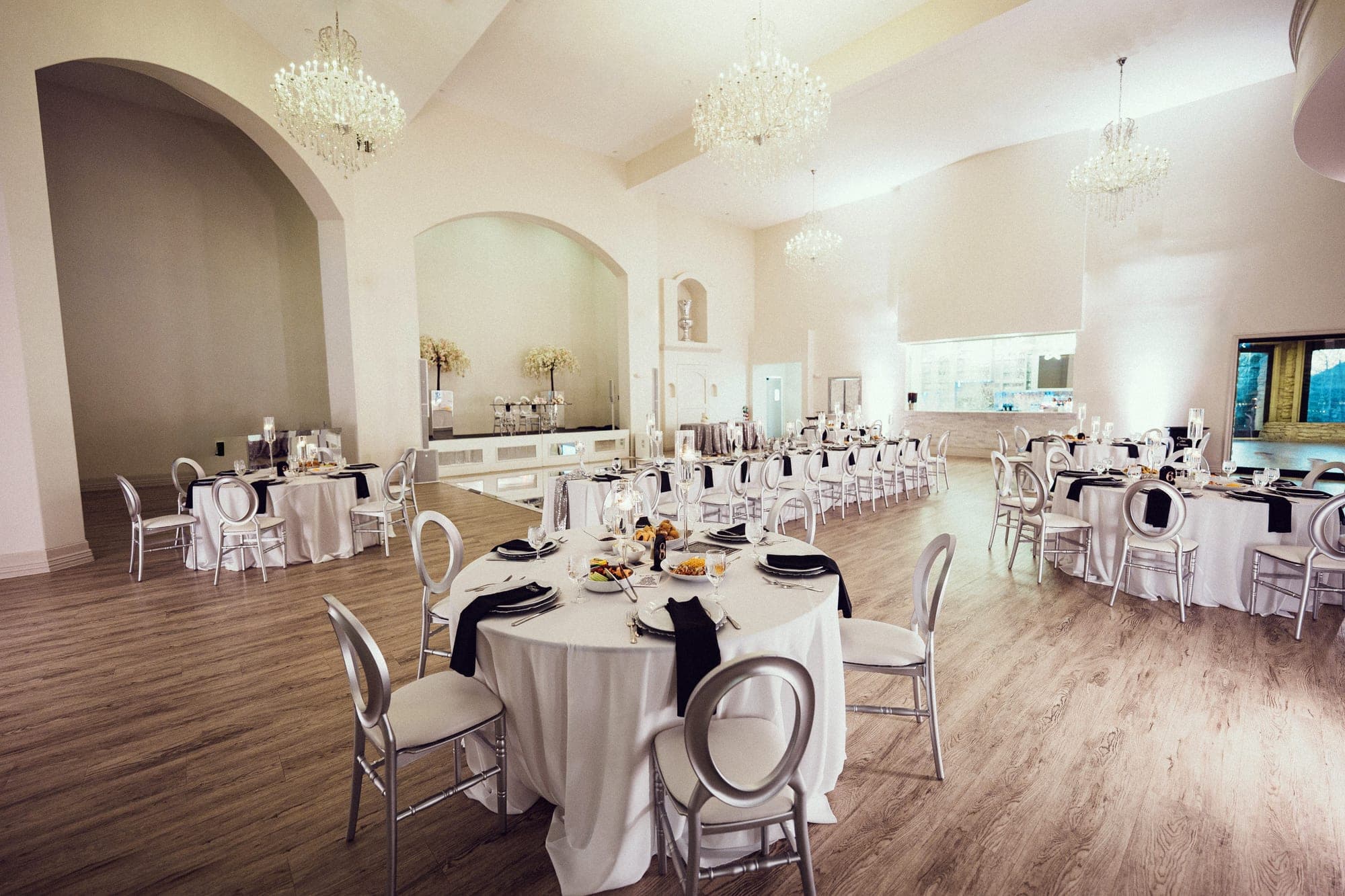 The ballroom at Knotting Hill Place dressed in white with chandeliers overhead