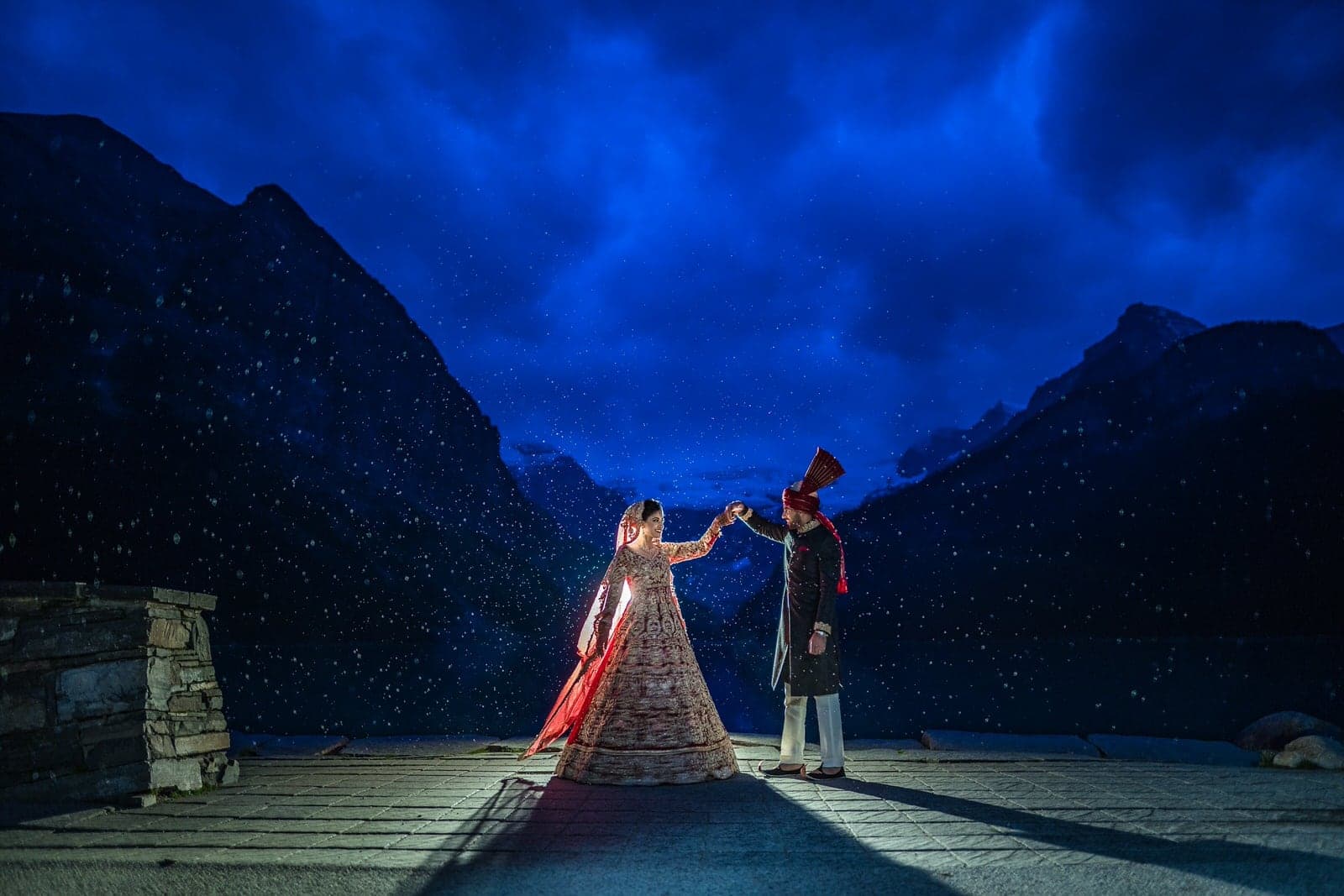 Lubna and Waqas silhouetted against the mountain lake at night
