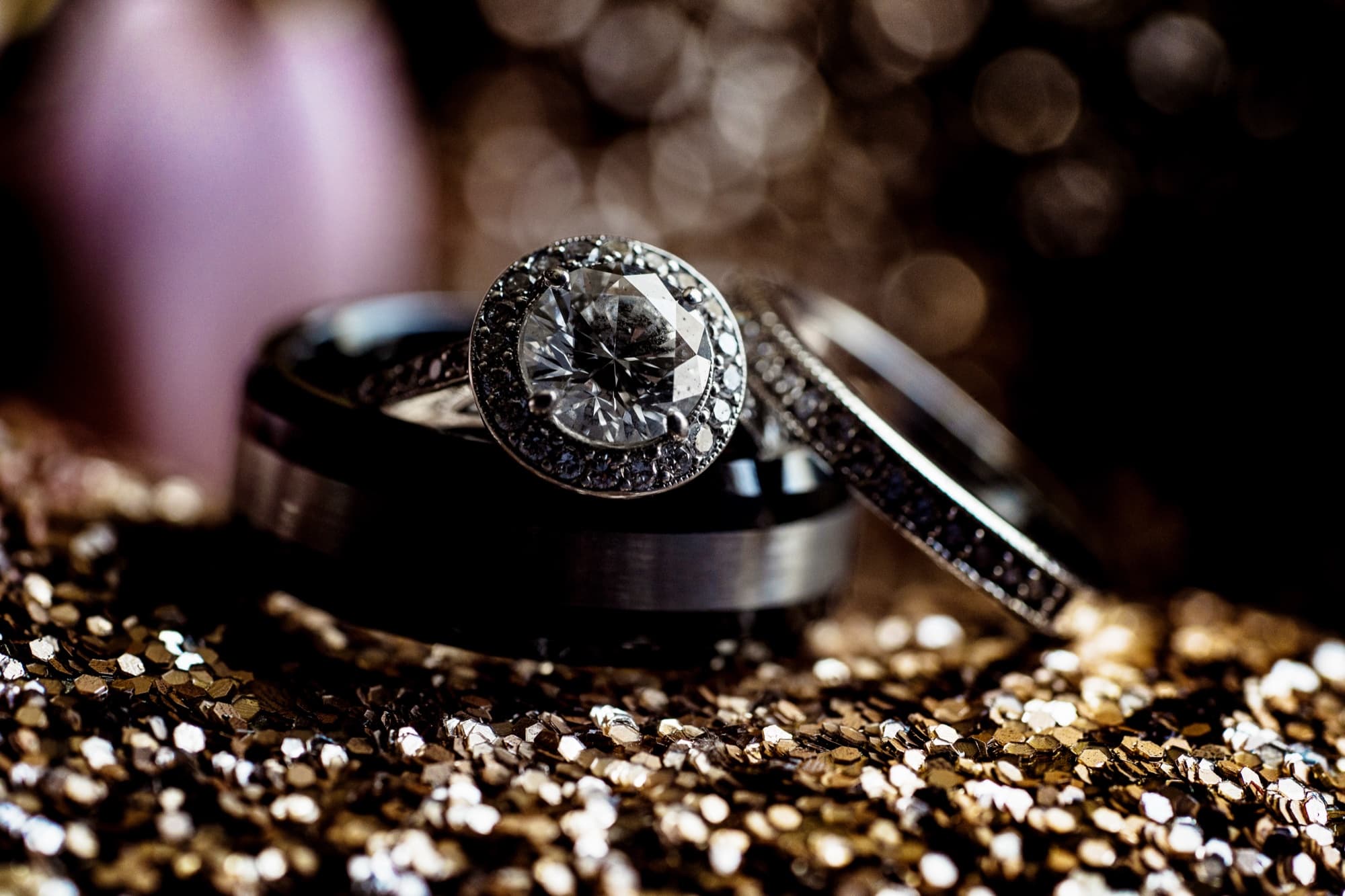 Halo diamond engagement ring and bands staged on gold glitter before a Langham Huntington Pasadena wedding