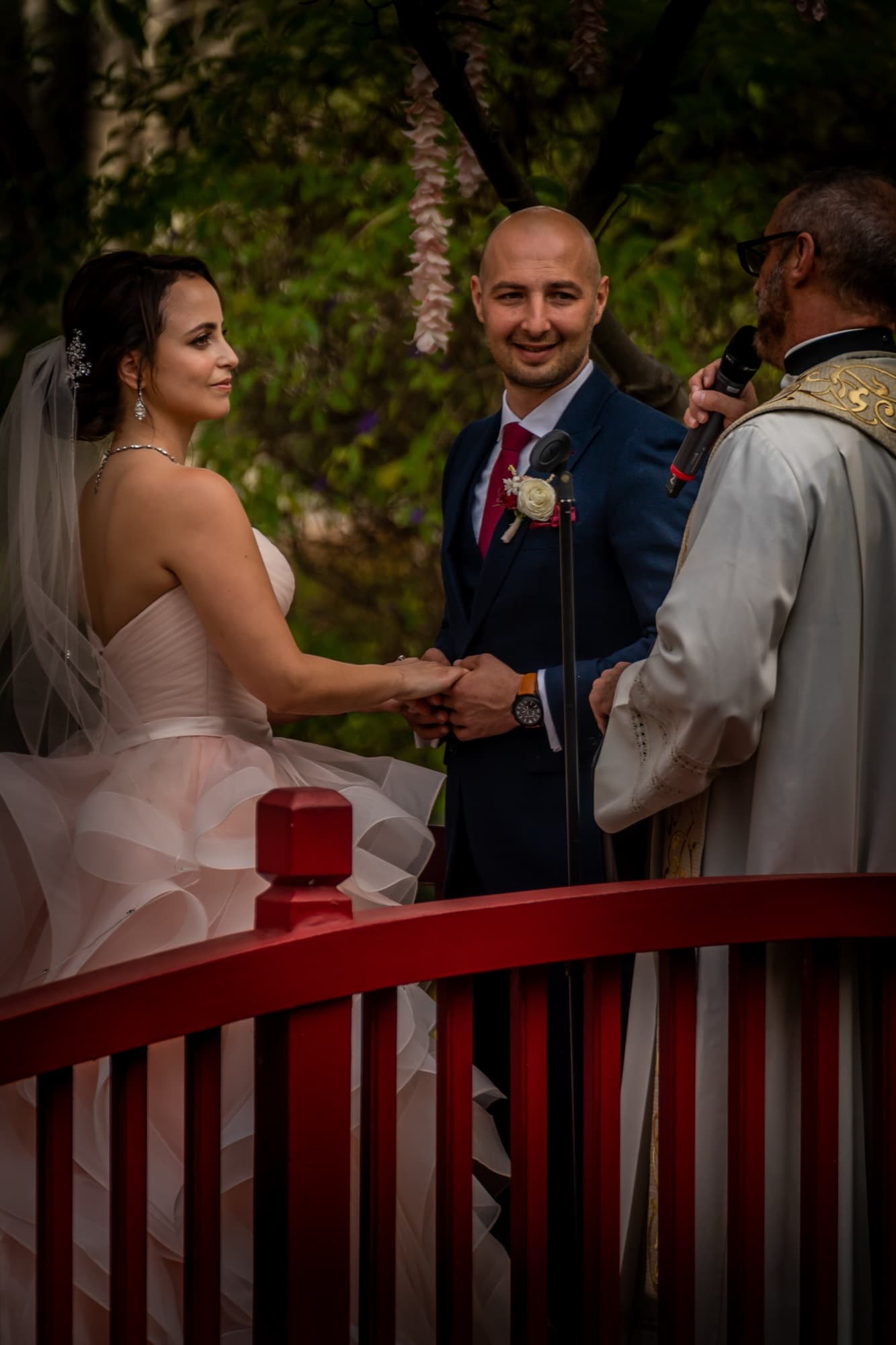 Wedding vows on the red garden bridge at The Langham Huntington Pasadena, the bride's blush gown ruffling over the rail