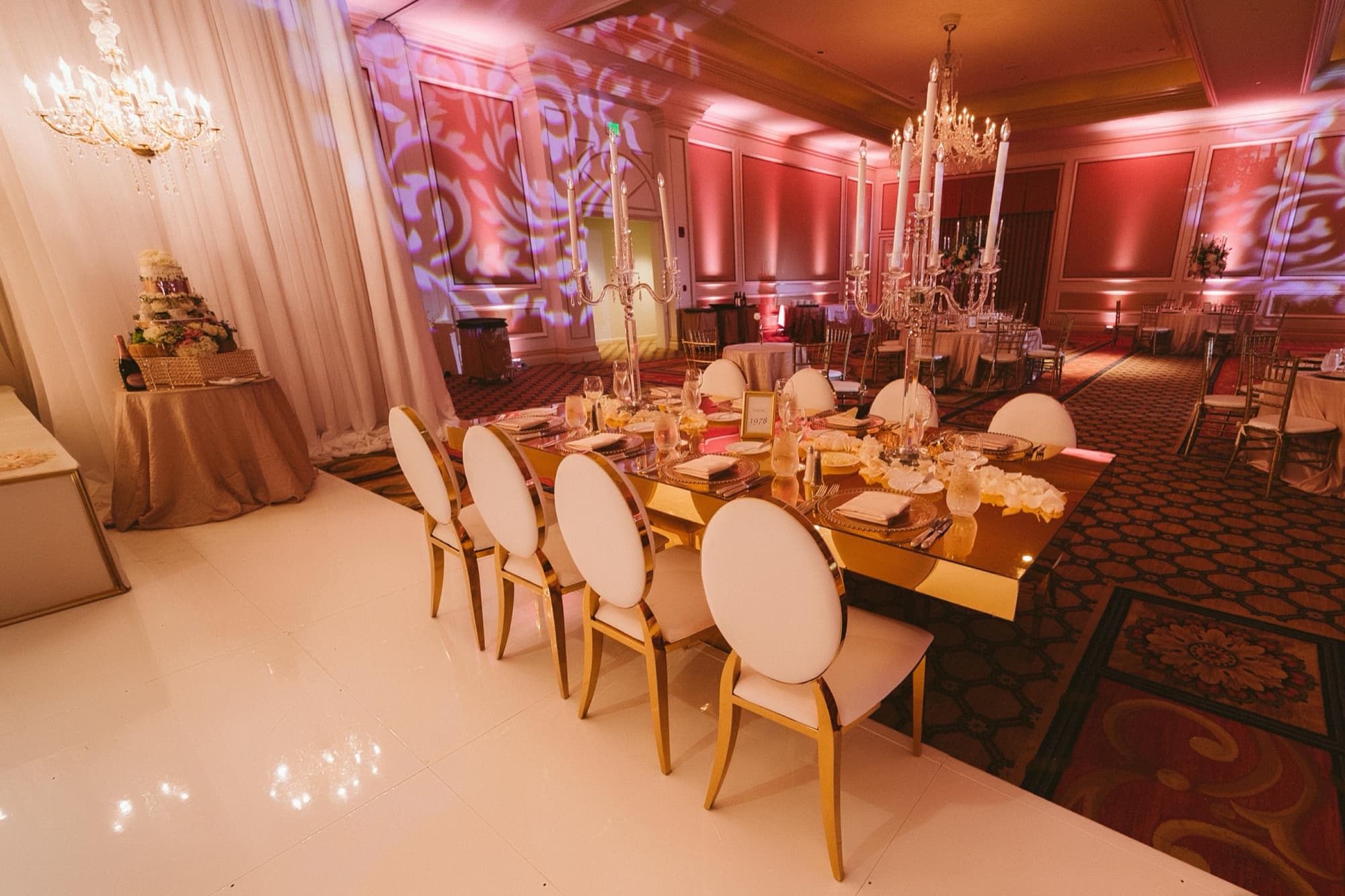 The Langham Pasadena grand ballroom with gold chairs, mirrored tables, and crystal candelabras lit in warm rose light
