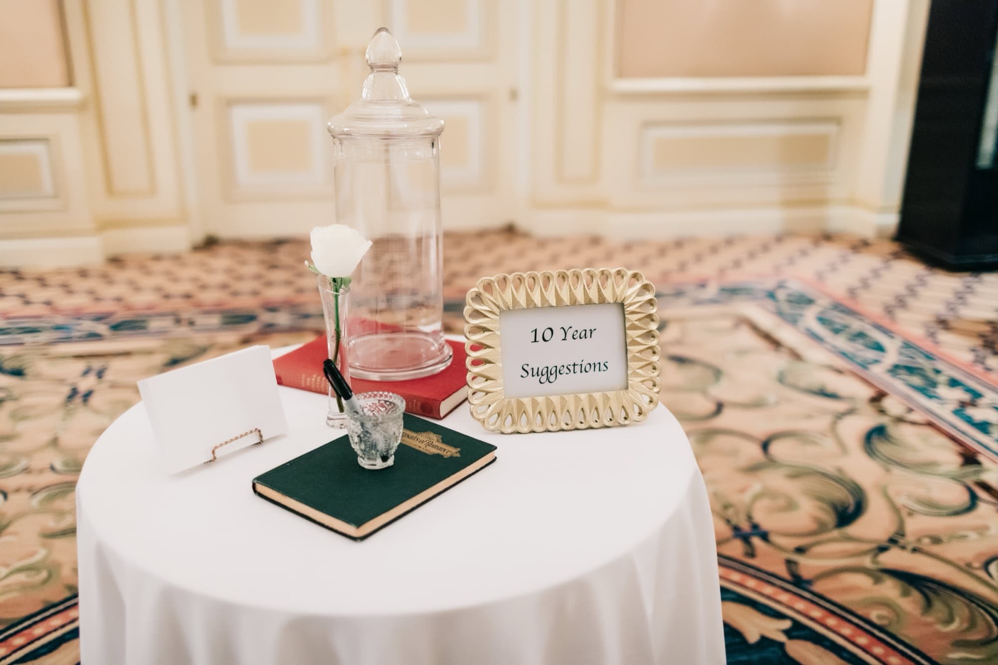 Guest book table at the Langham with a card asking guests for ten-year marriage advice beside a single white rose