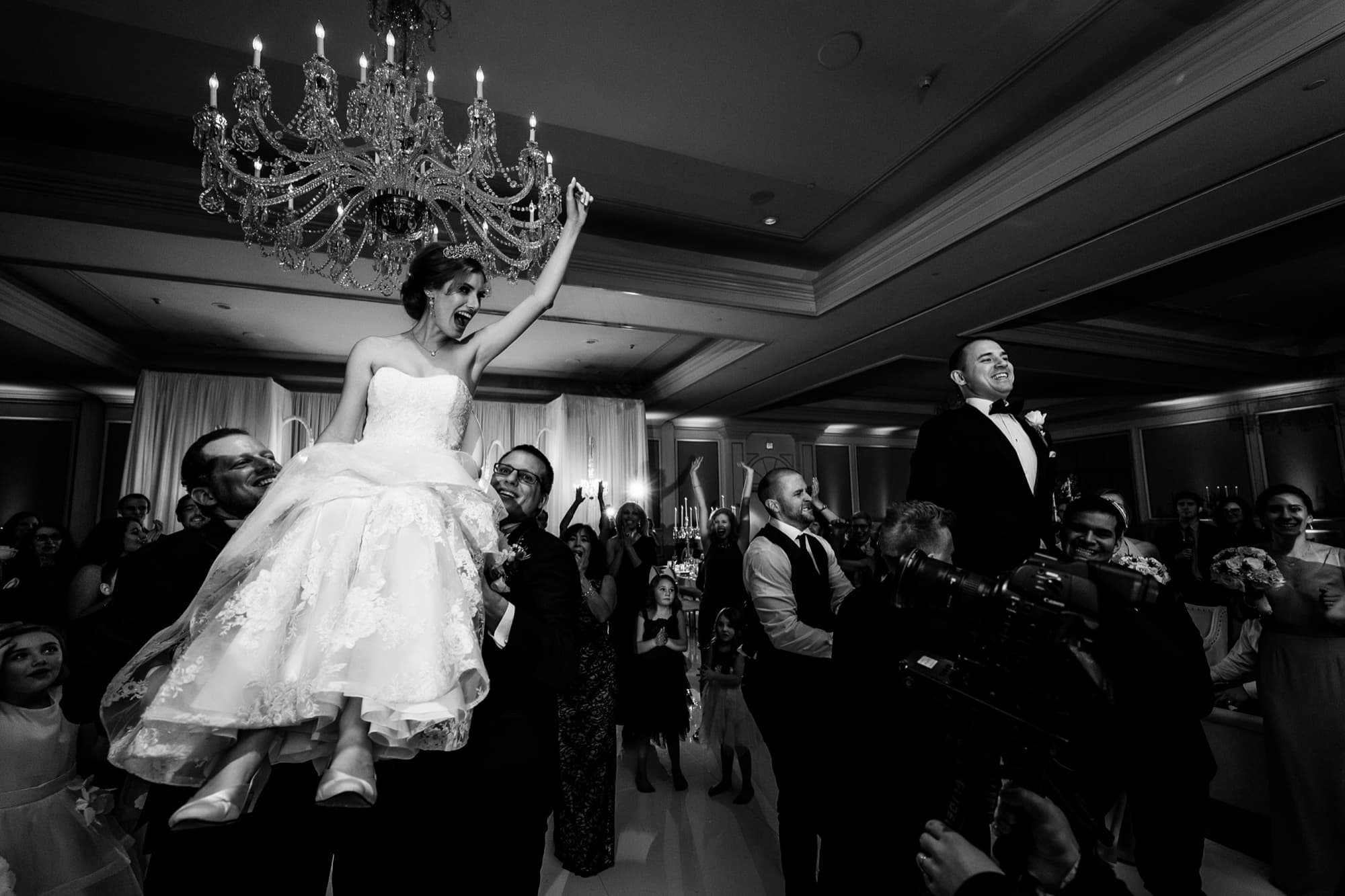 Black and white photograph of Ilana lifted on a chair during the hora at her Langham Pasadena wedding