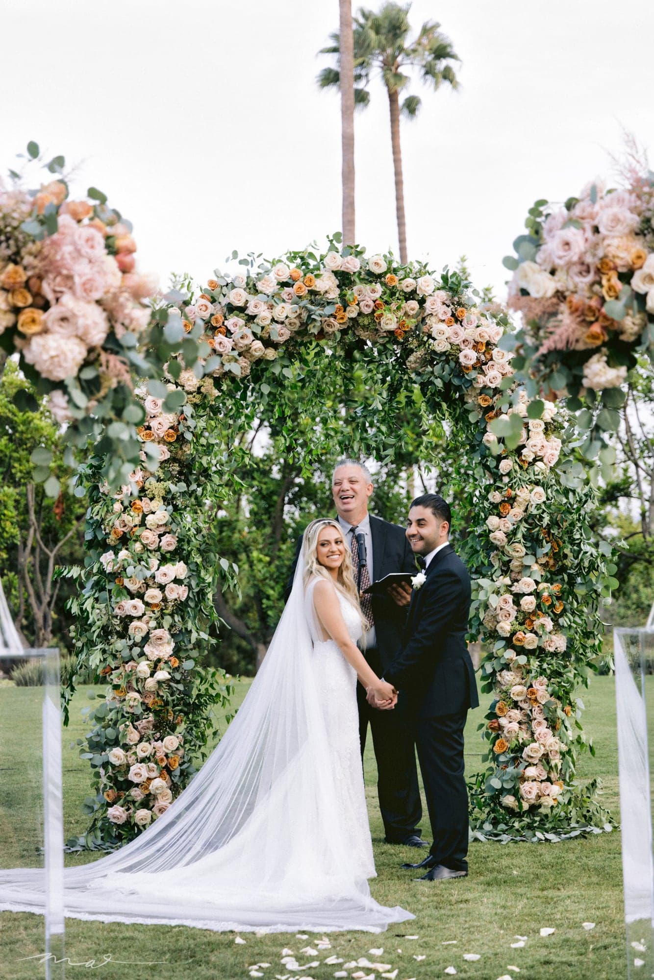 Melody and Hrand beneath the garden ceremony flowers