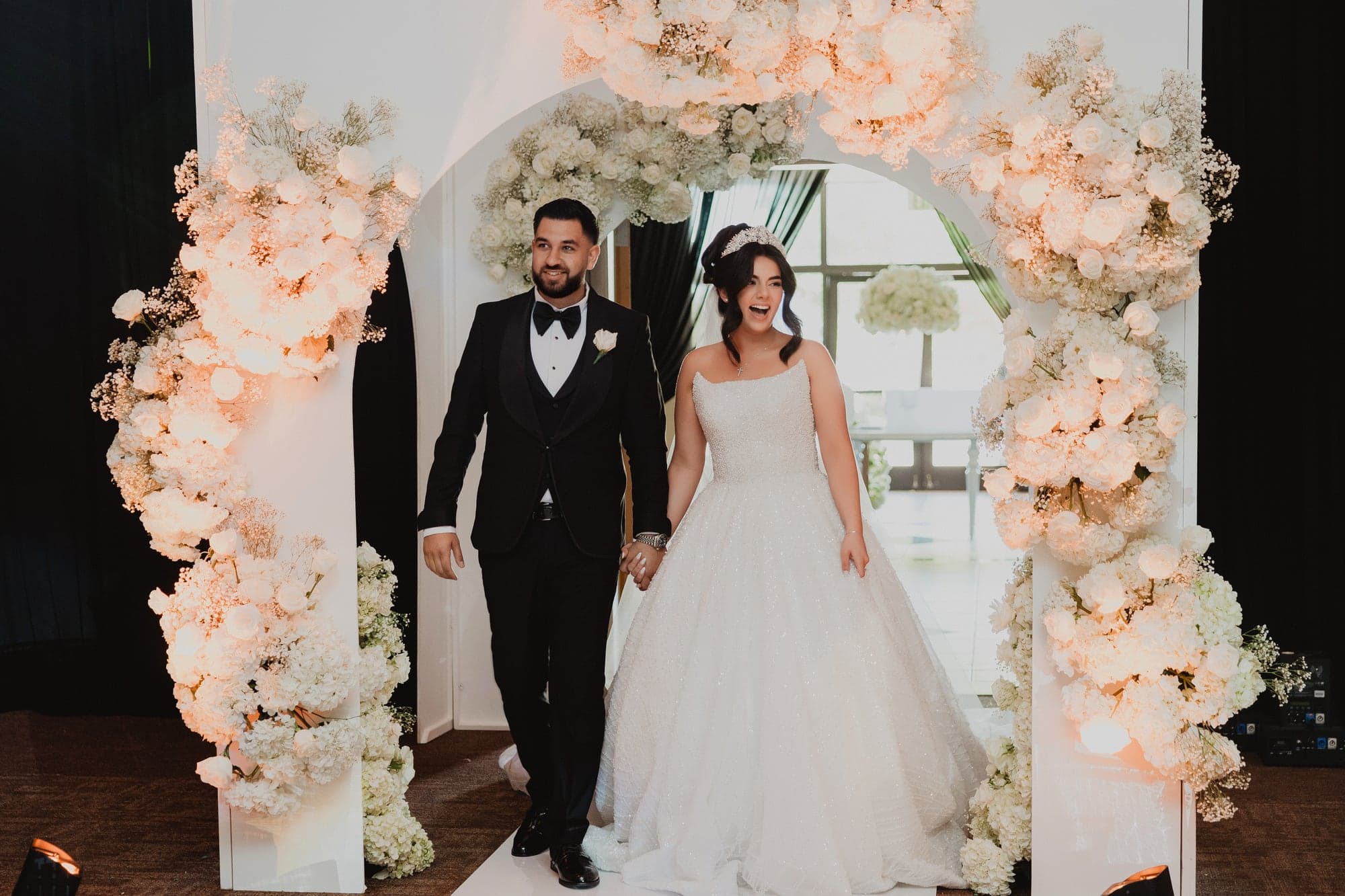 Amanda and Anthony entering the reception through a floral arch