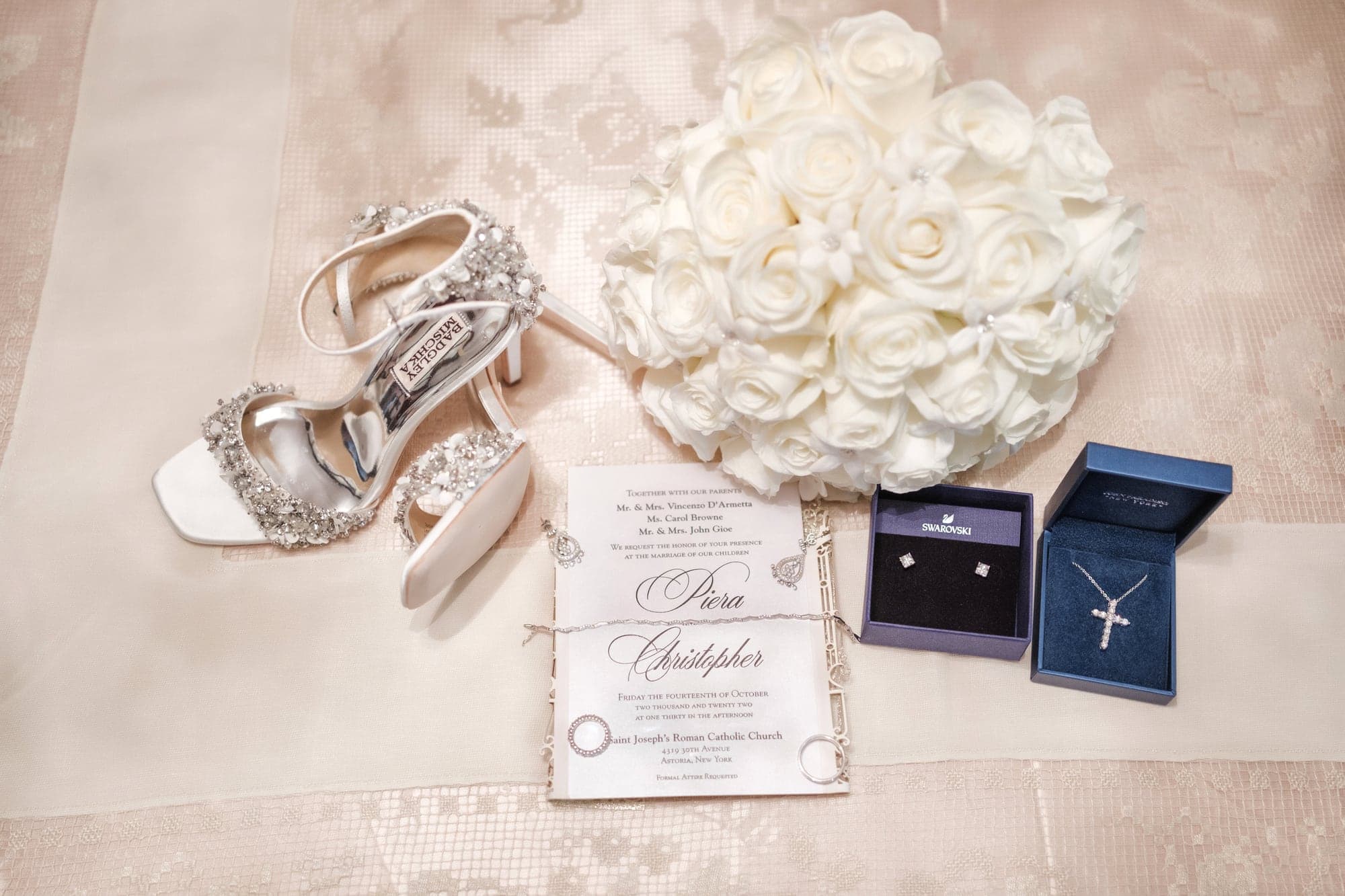 Silver wedding shoes, rings, stationery, and white flowers arranged before the Legacy Castle wedding