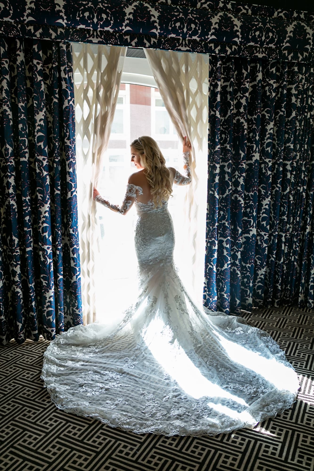 Jaymie in a window backlight with her beaded lace train fanned across the patterned floor at the Los Angeles Athletic Club