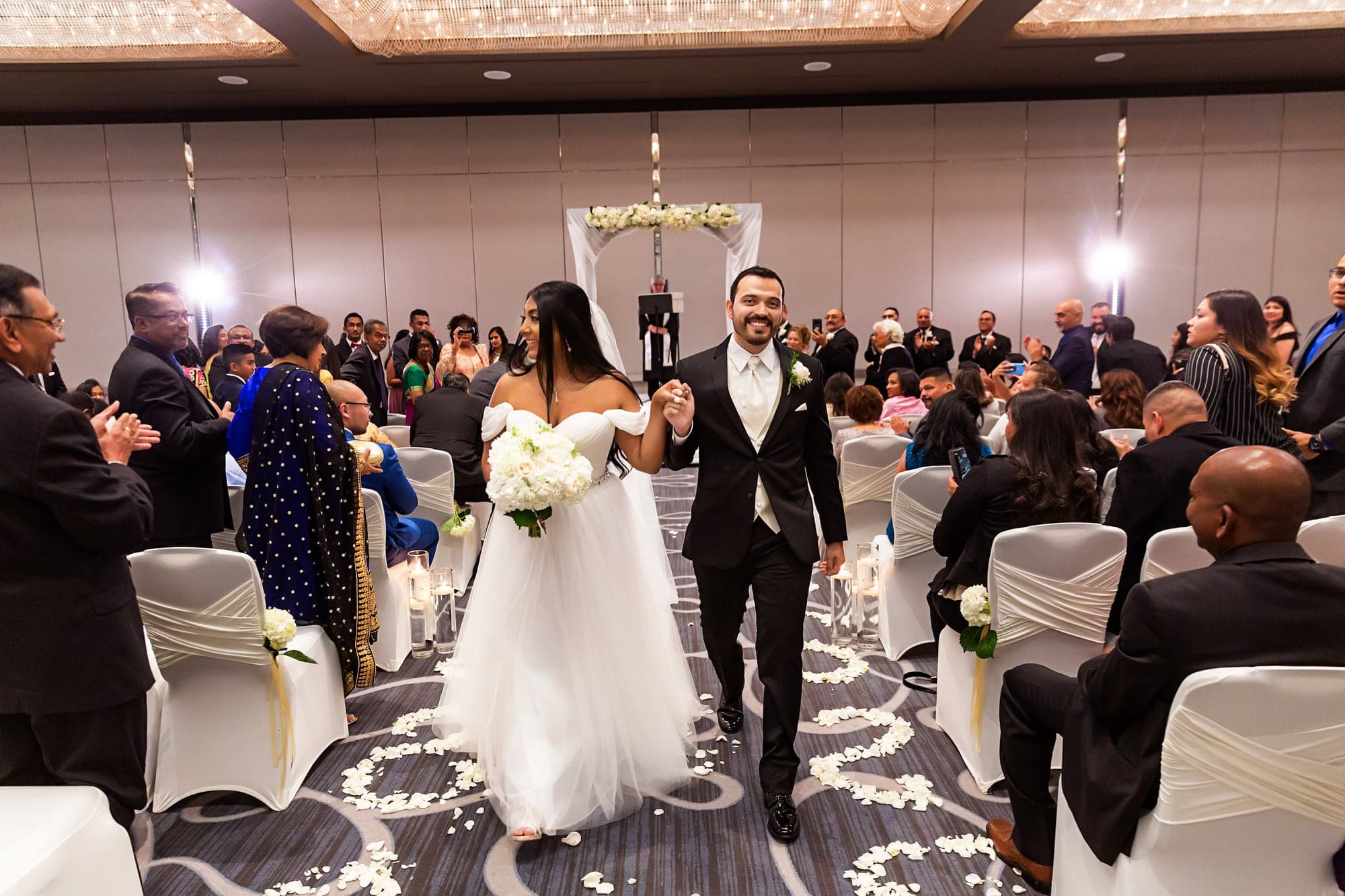 Tari and JJ walking together after their indoor wedding ceremony