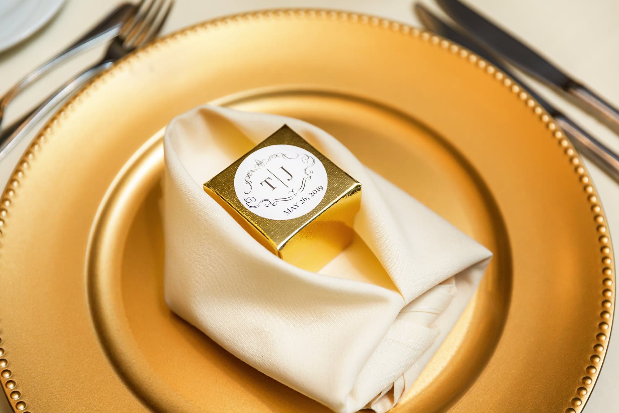 A gold wedding favor monogrammed with Tari and JJ's initials