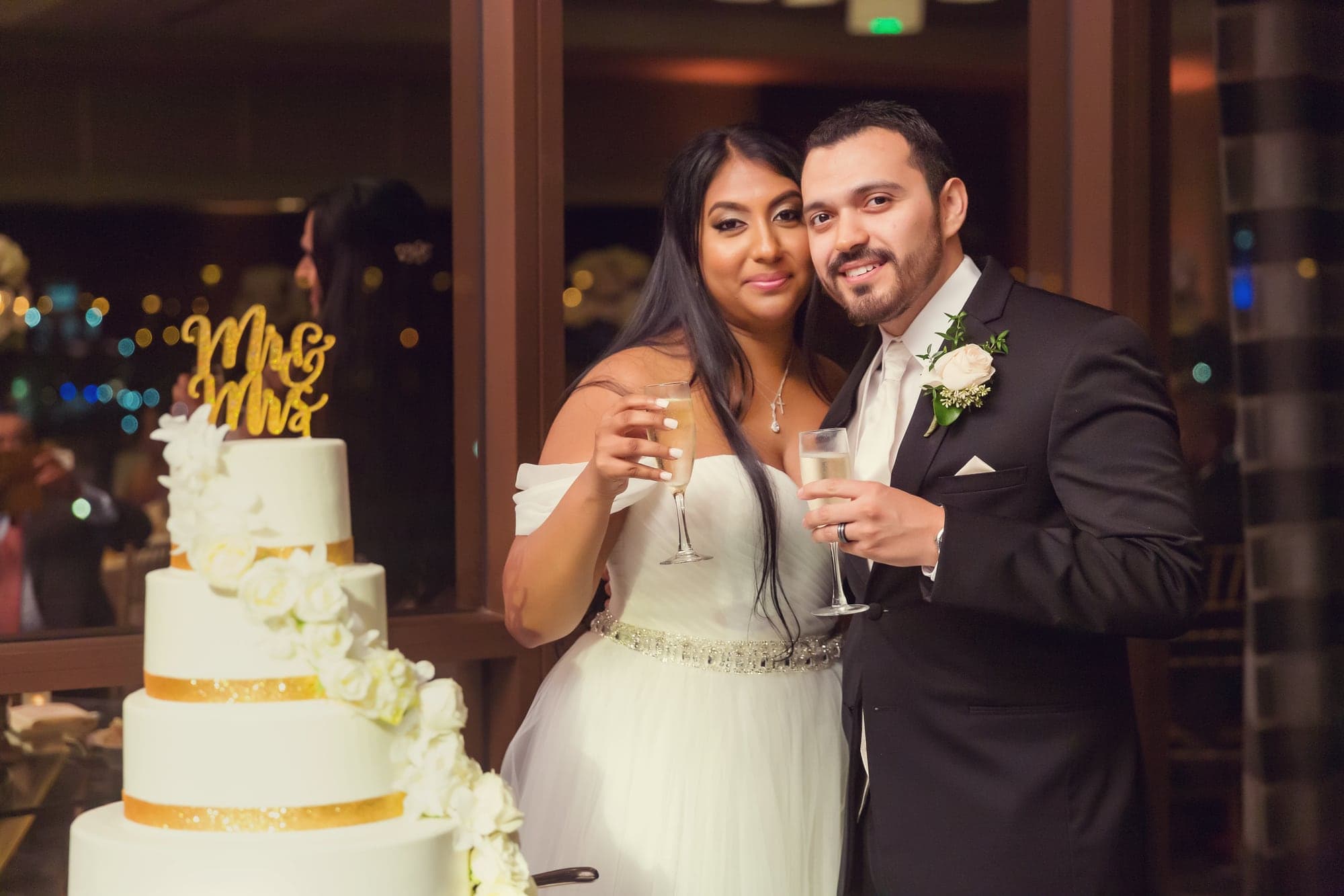 Tari and JJ kissing beside their wedding cake