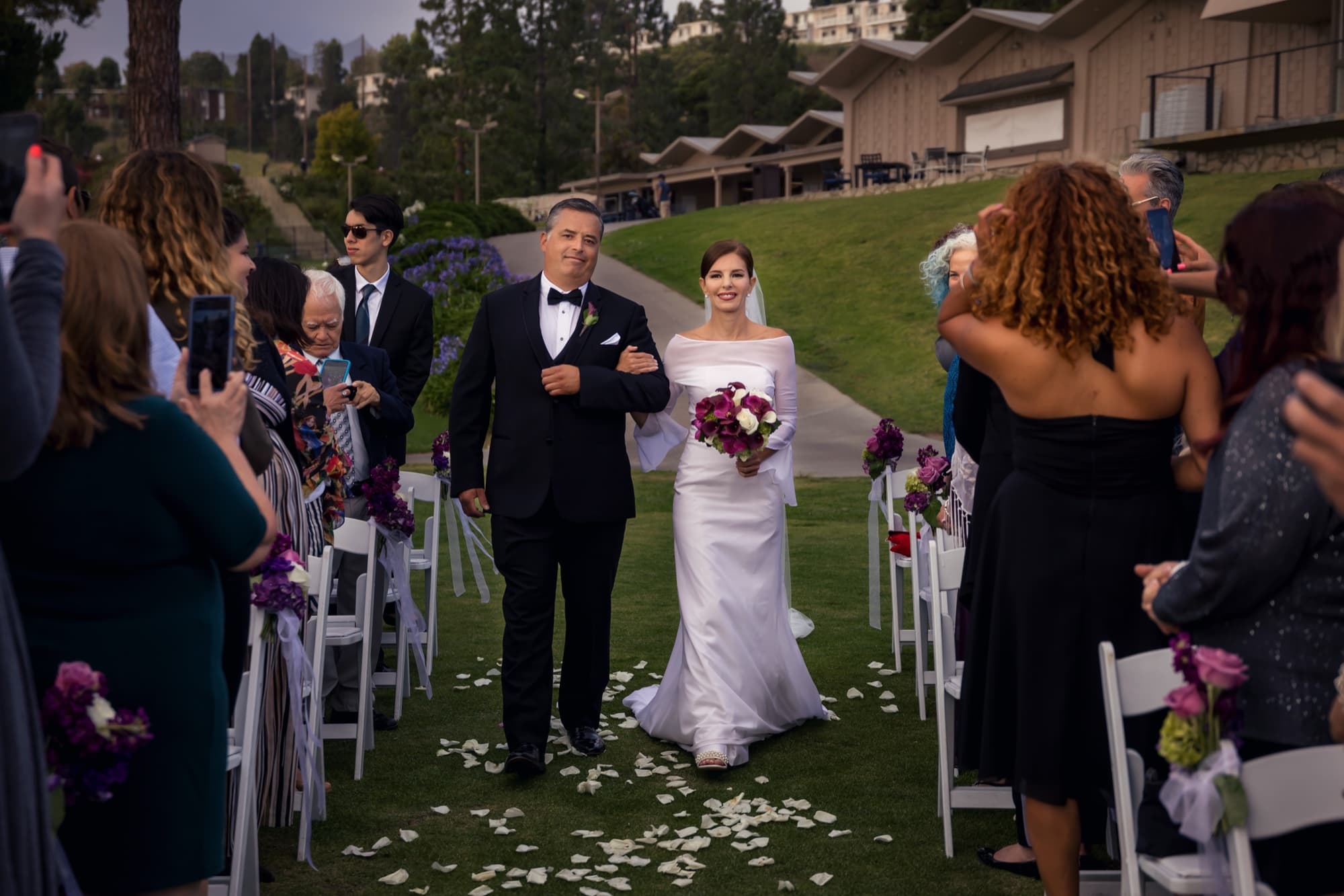 Andrea walking down the white-petal aisle on her father's arm at her Los Verdes Golf Course ceremony