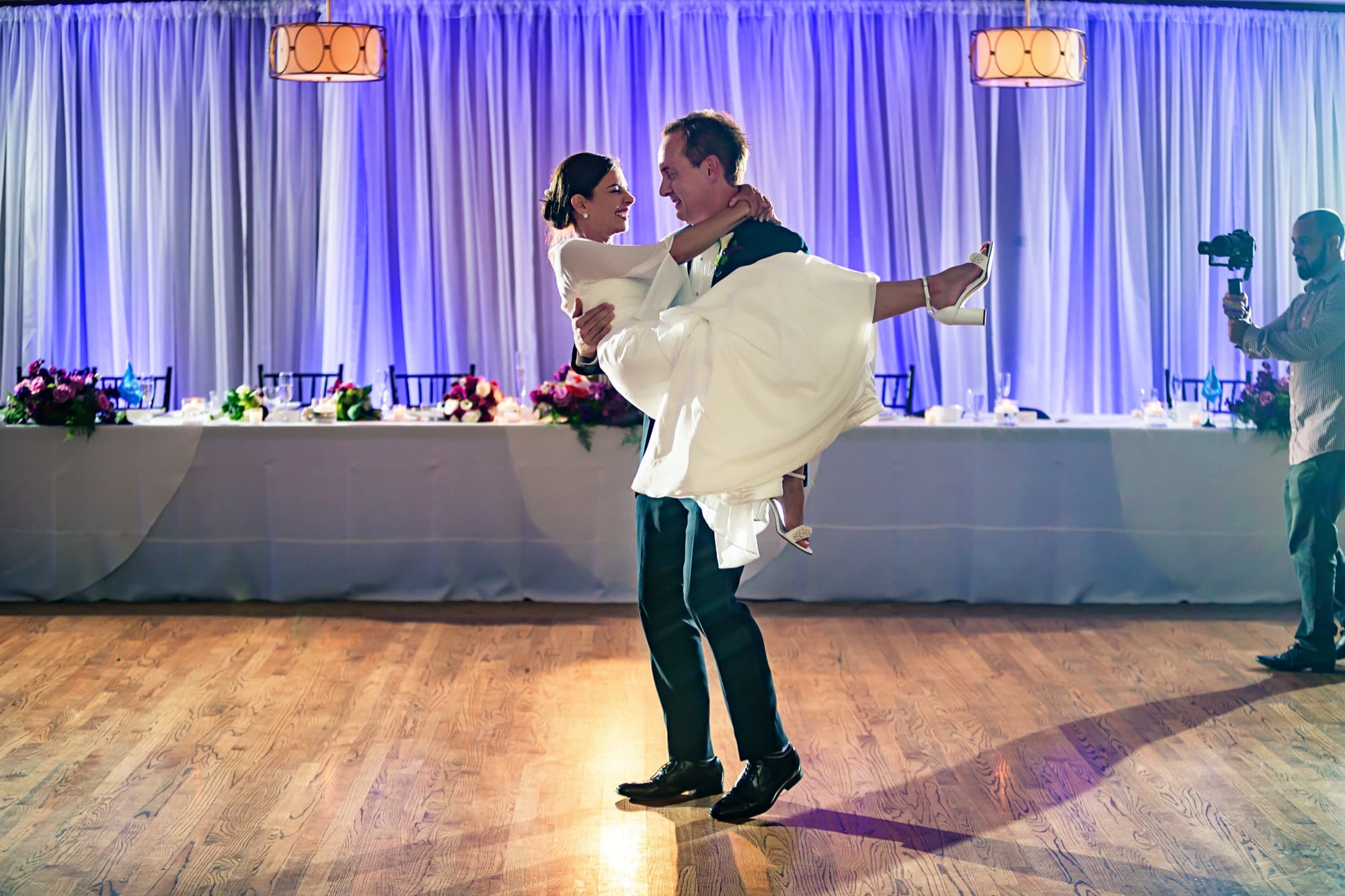 John lifting Andrea in his arms on the dance floor of the purple-lit Los Verdes ballroom