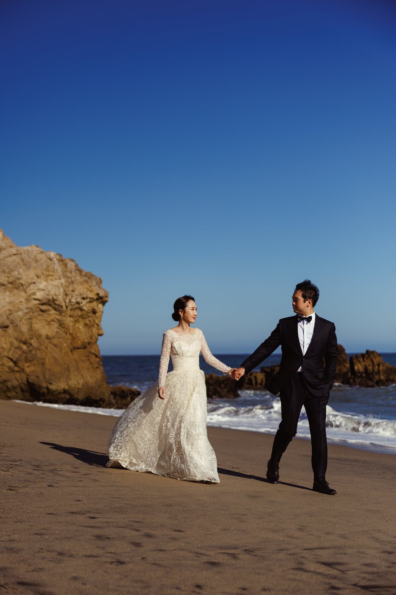 Lauren and Lee walking together beside the rocky shoreline
