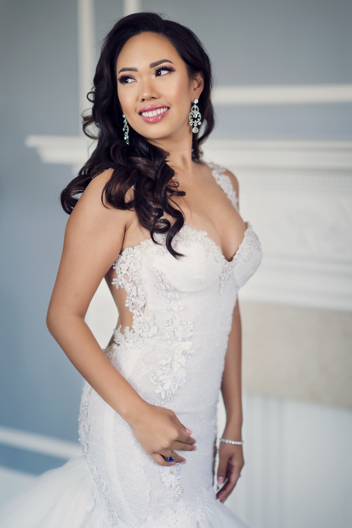 Bridal portrait of Caroline in a lace mermaid gown with chandelier earrings in soft window light