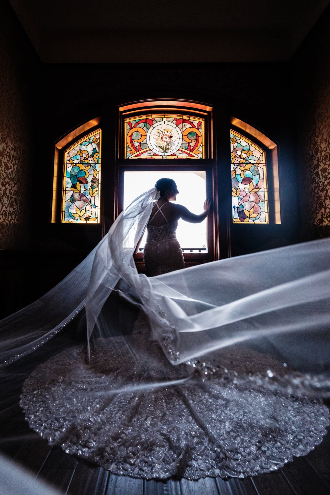 Haley standing in stained glass window light before the ceremony