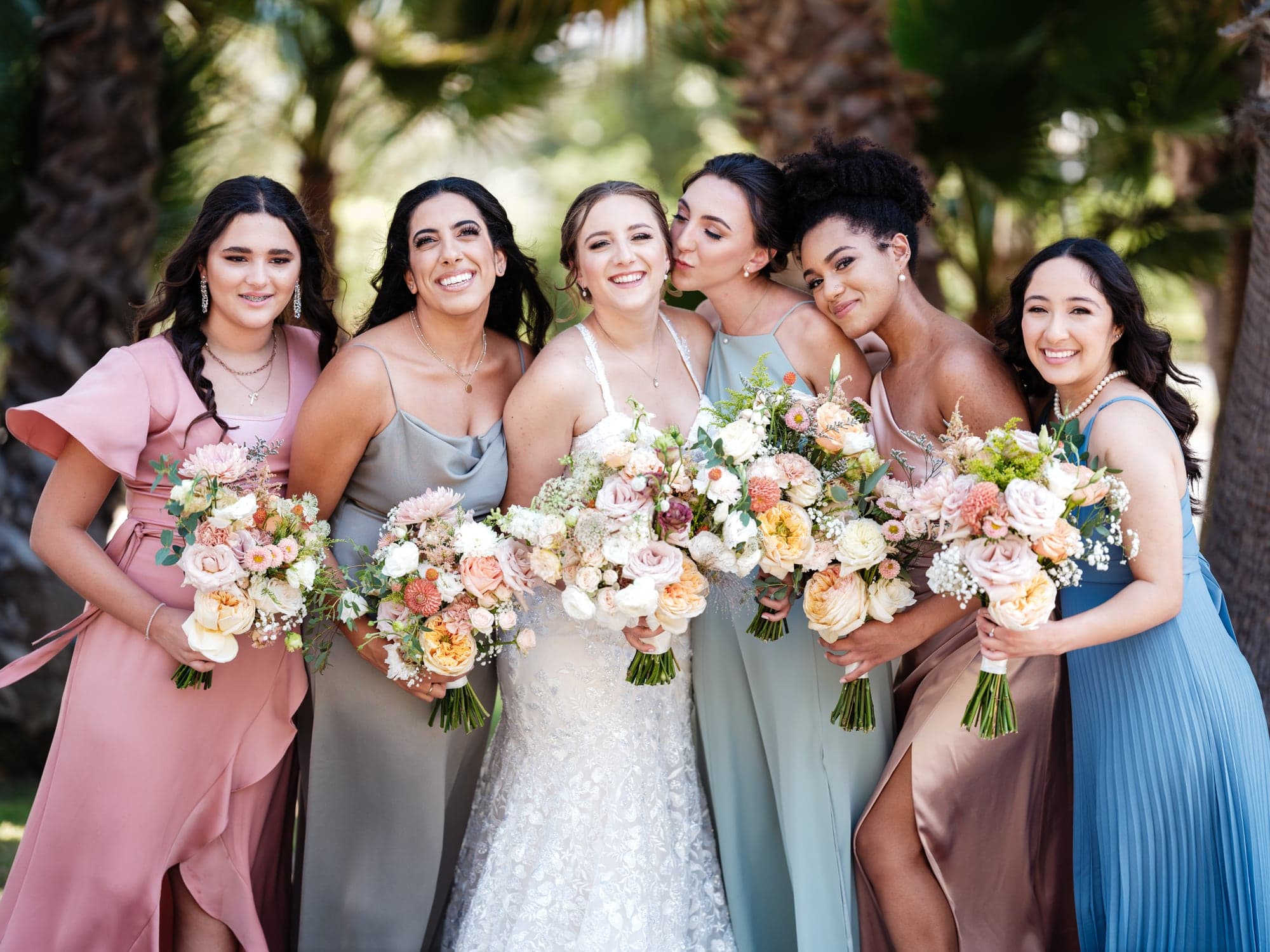 Haley and her bridesmaids holding pastel bouquets outside Newhall Mansion