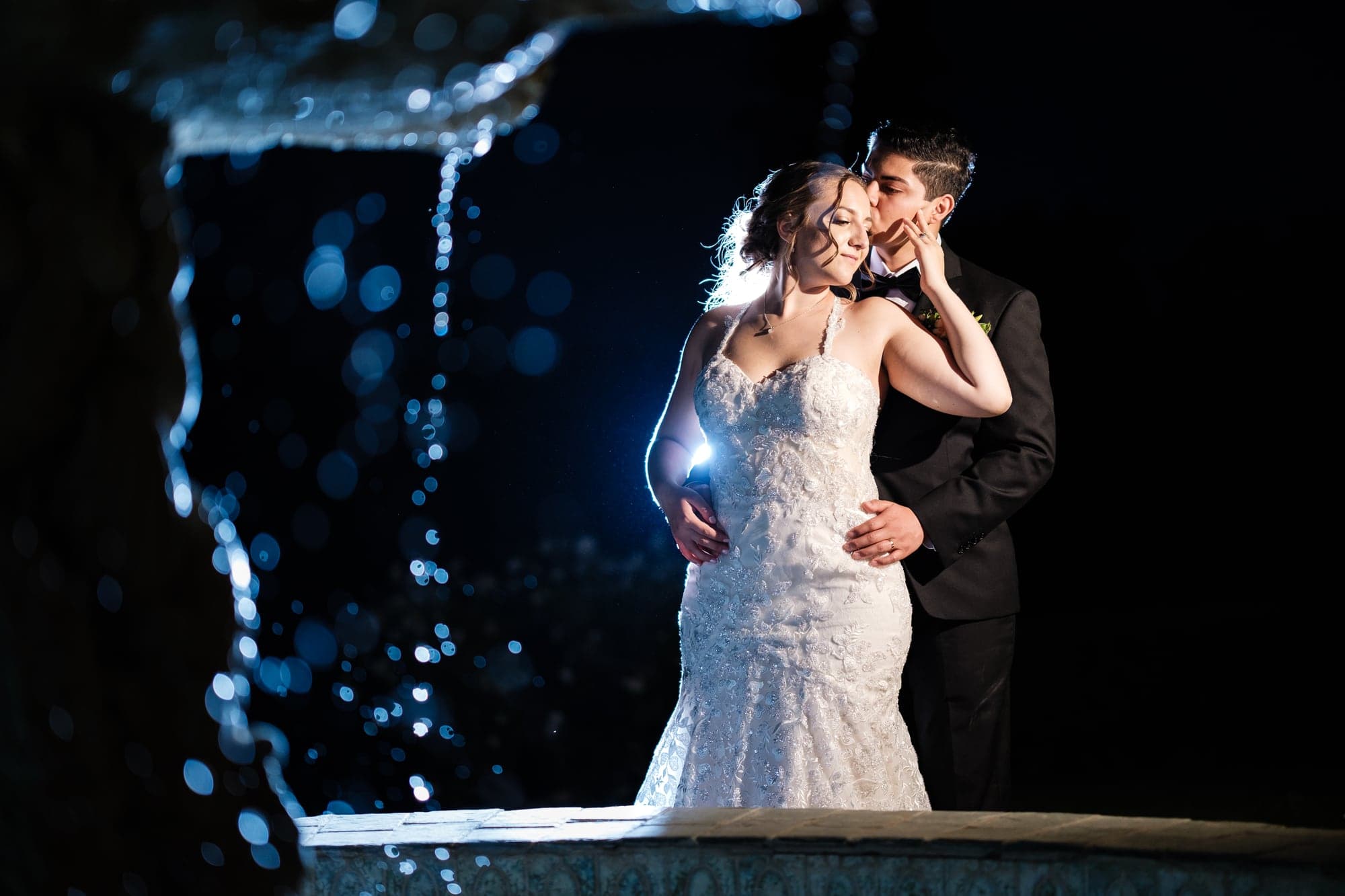 Haley and Clayton dancing in front of illuminated water at the reception