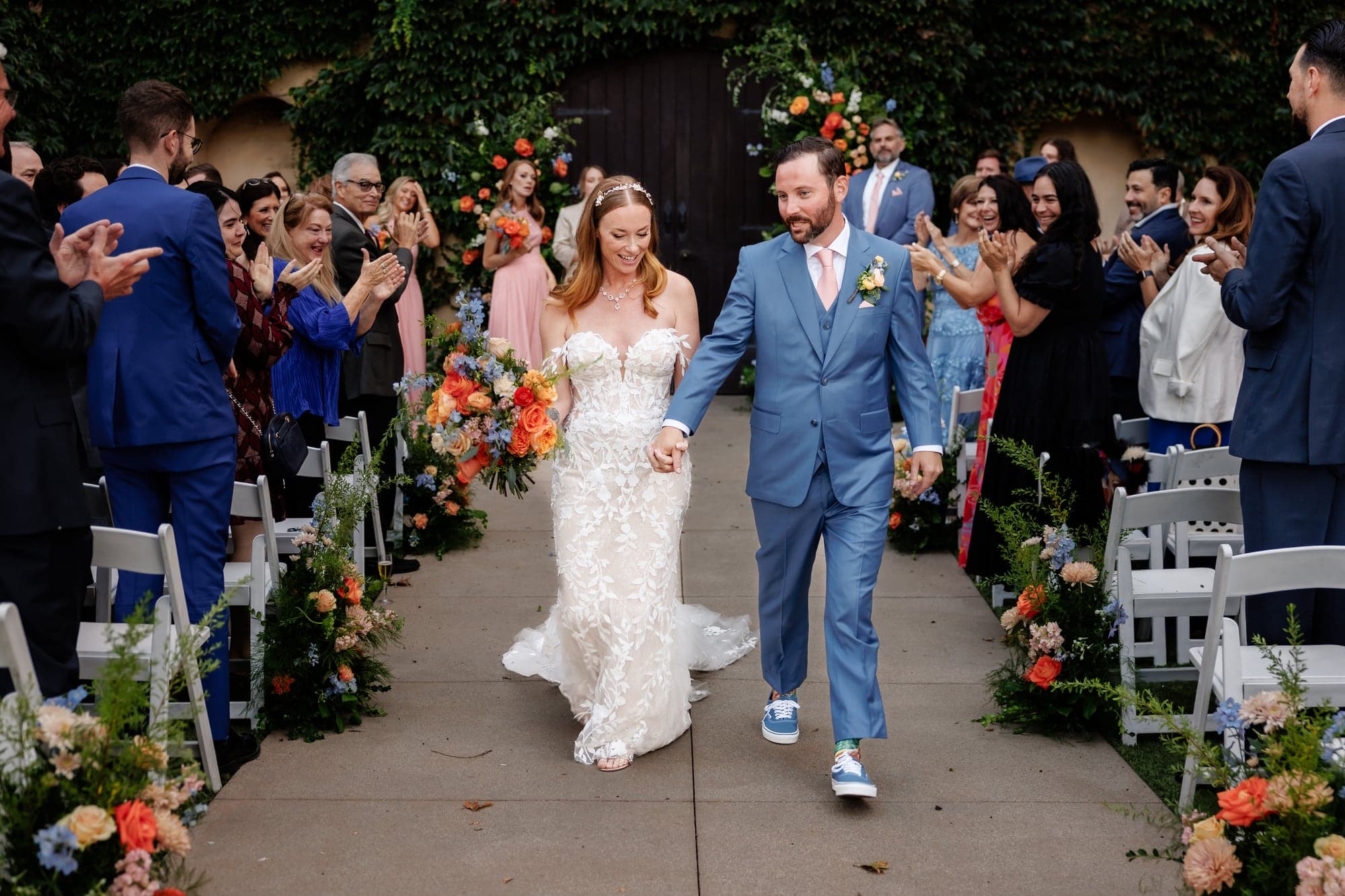 Katie and Matthew walking back up the aisle as guests celebrate