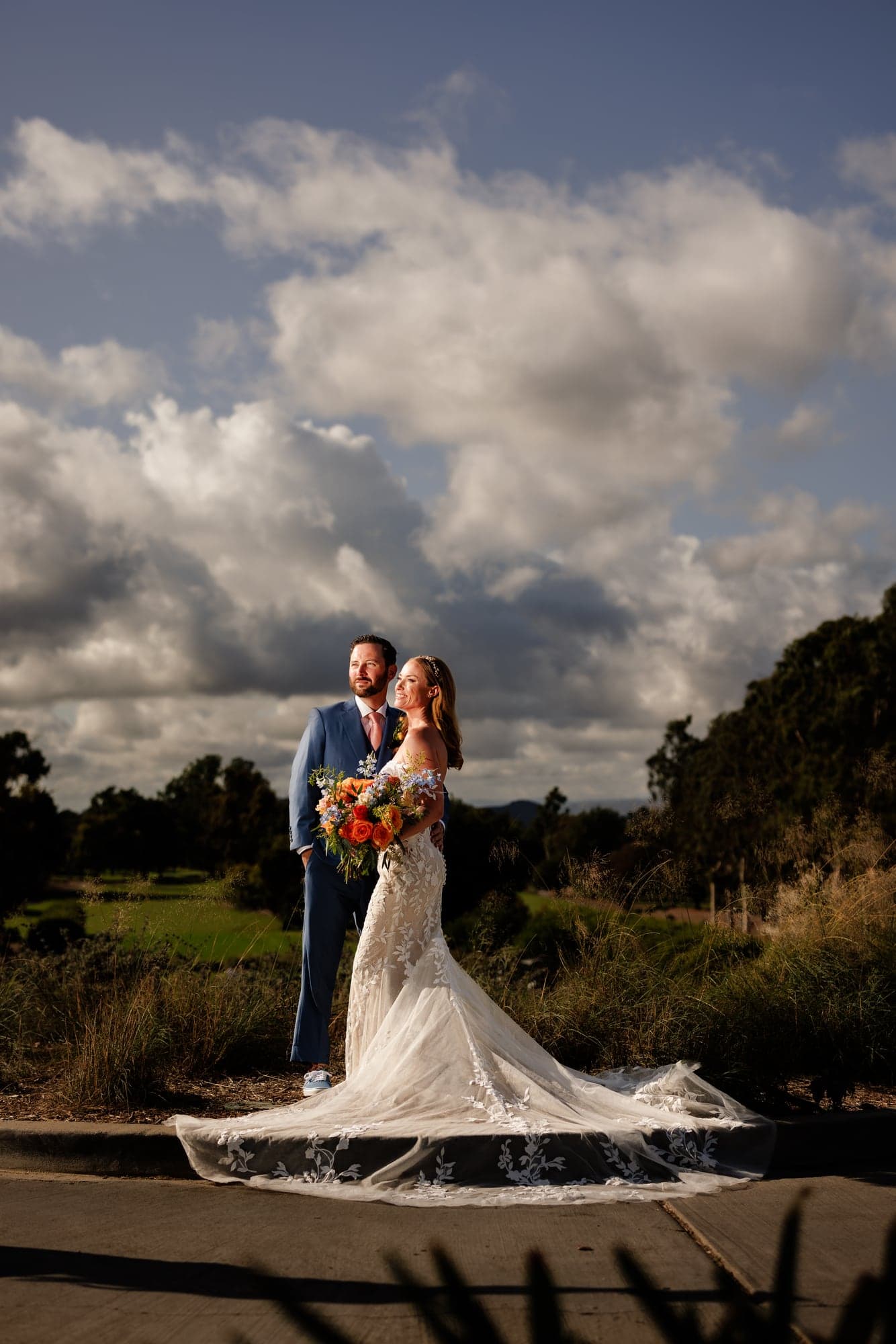 Katie and Matthew standing together beneath dramatic evening clouds