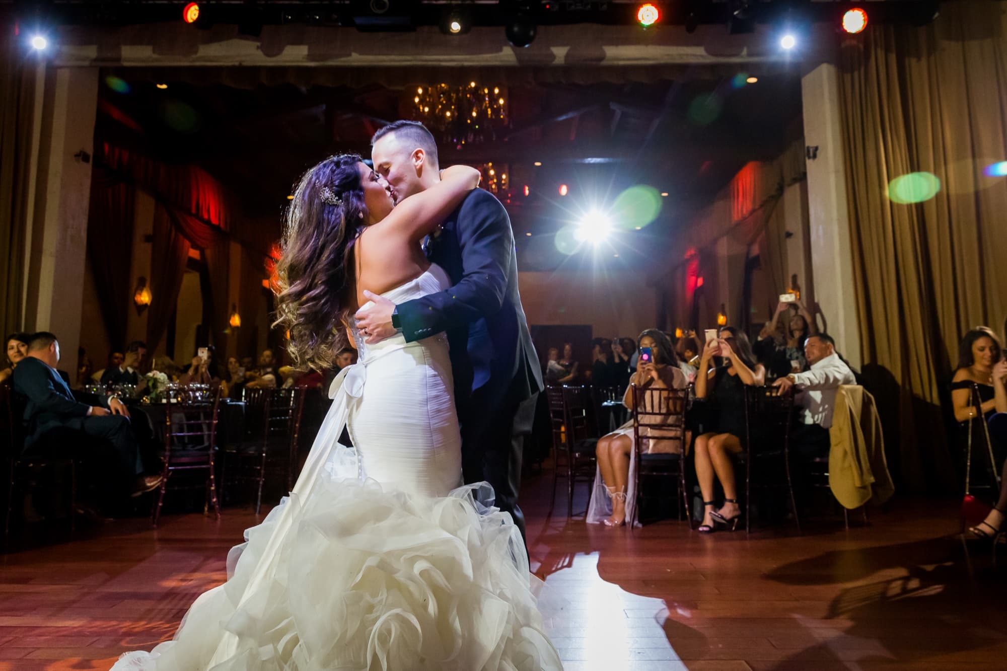Soraya and Donald kissing in the spotlight during their first dance on the historic stage at Padua Hills Theatre