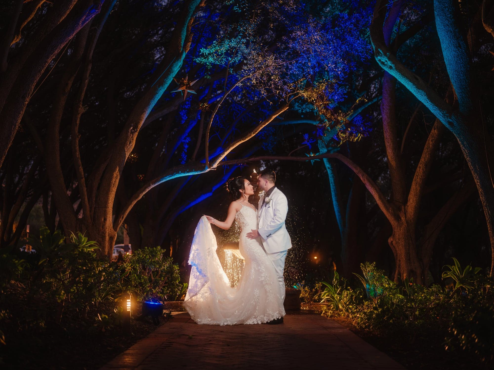 Mayling and David embracing beneath blue-lit trees after their Padua Hills wedding