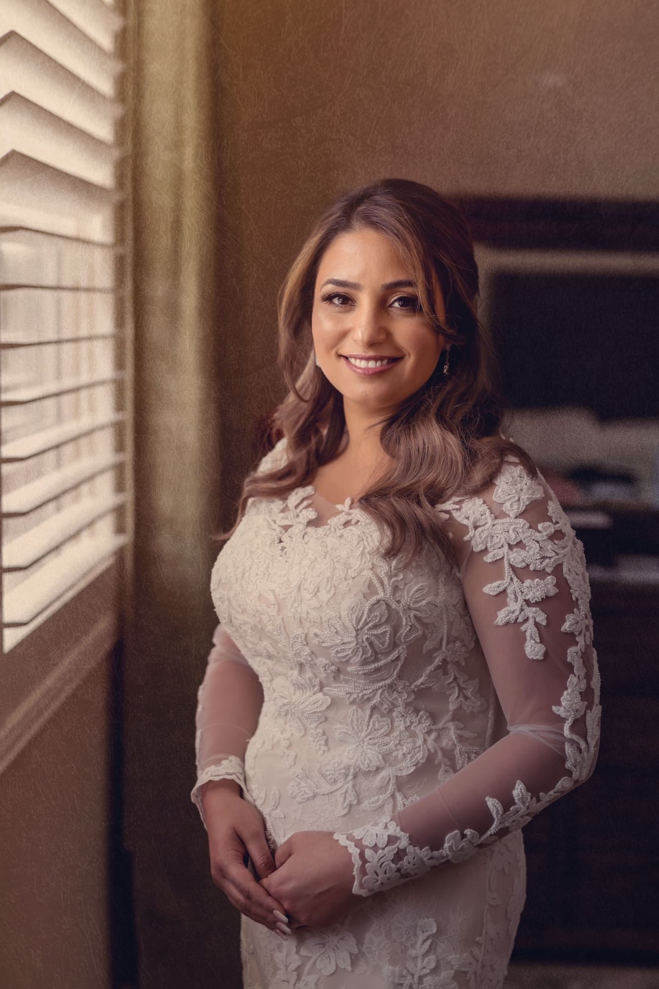 Yomna in her long-sleeve illusion-lace gown standing in soft window light with her hands folded