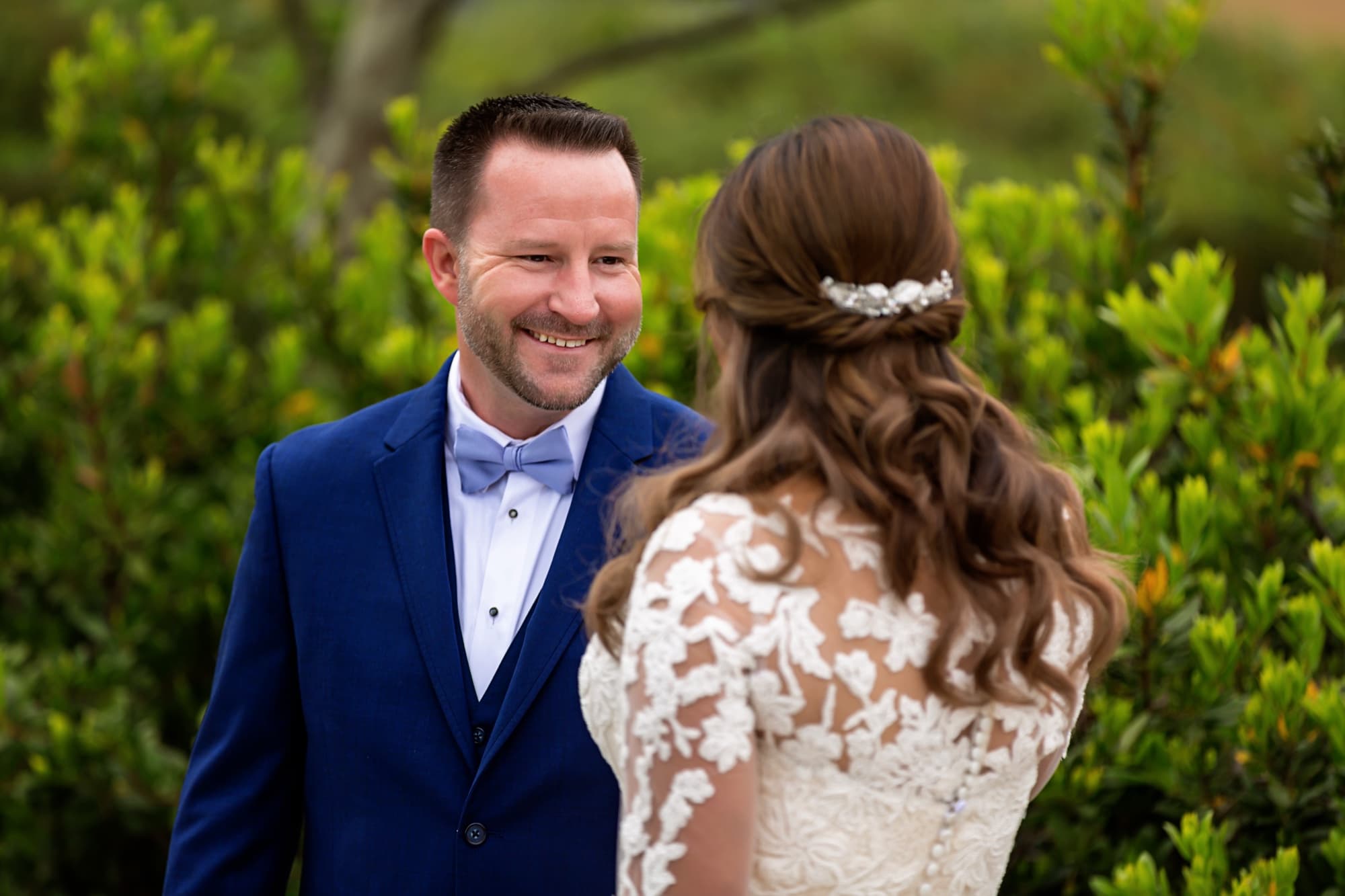 Bradley smiling broadly at Yomna during their first look in the garden, her lace back to the camera