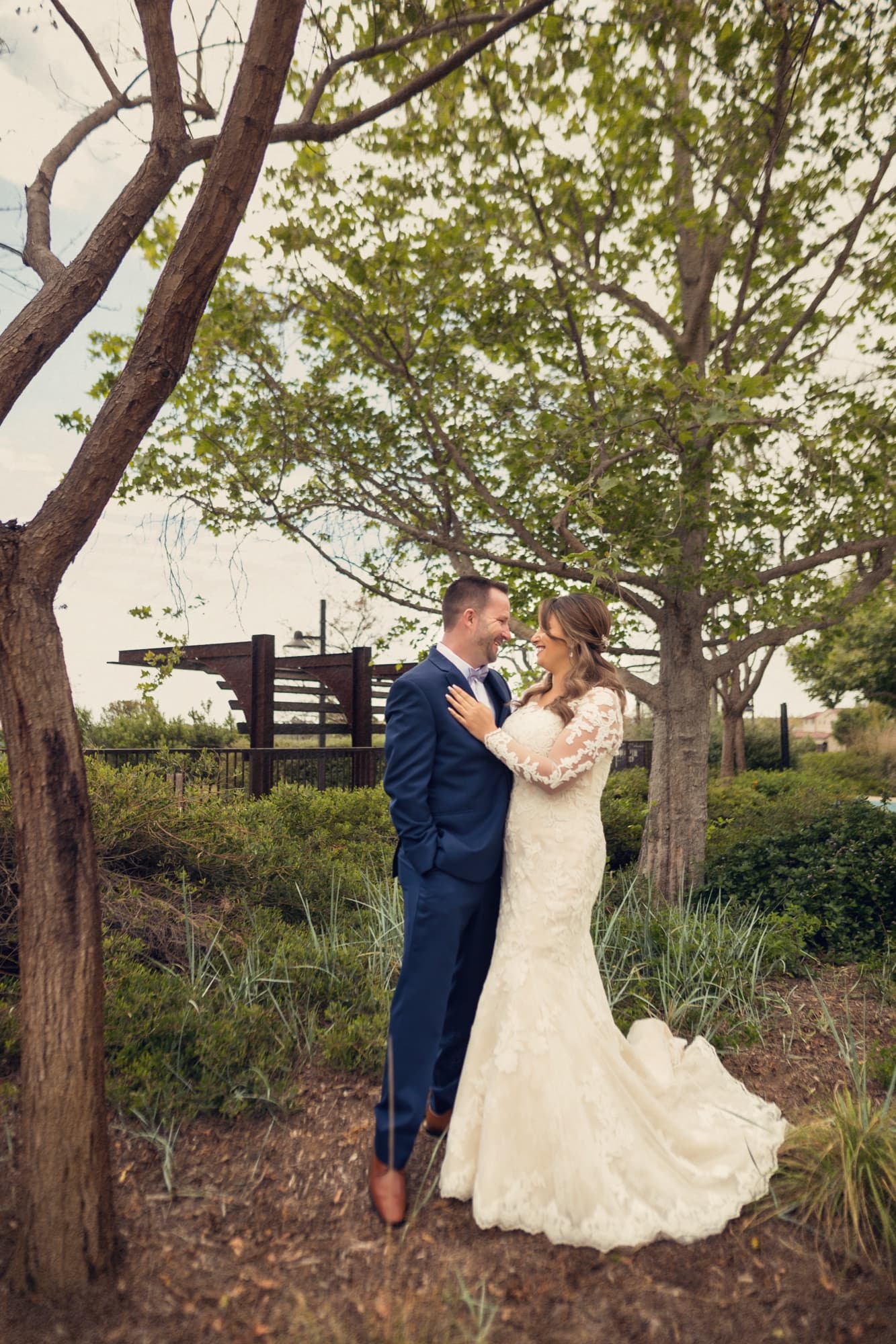 Bradley dipping Yomna for a kiss beneath spring trees, her gown trailing into the wild grass