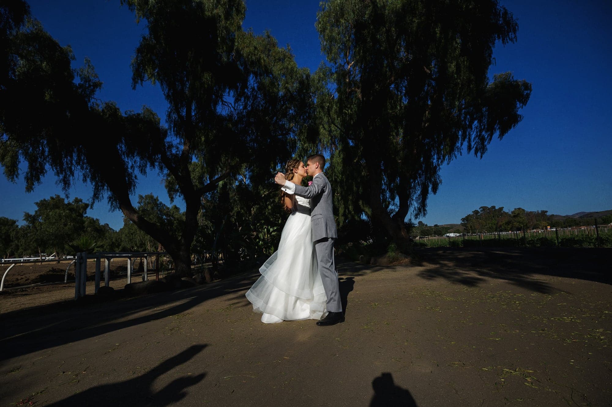 Mary and Cole standing together beneath the trees at Rancho De Las Palmas
